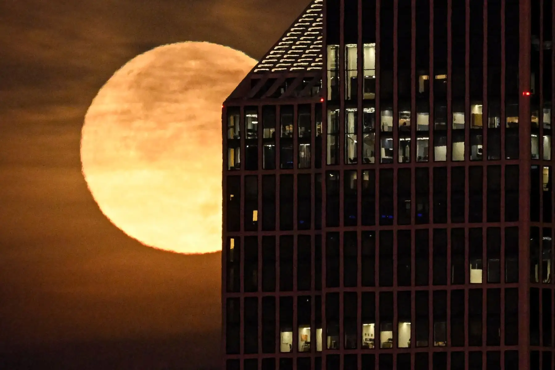 La luna llena de noviembre, también conocida como "Luna del Castor", aparece en la fotografía detrás de un edificio del distrito bancario de Fráncfort del Meno, en el oeste de Alemania. AFP