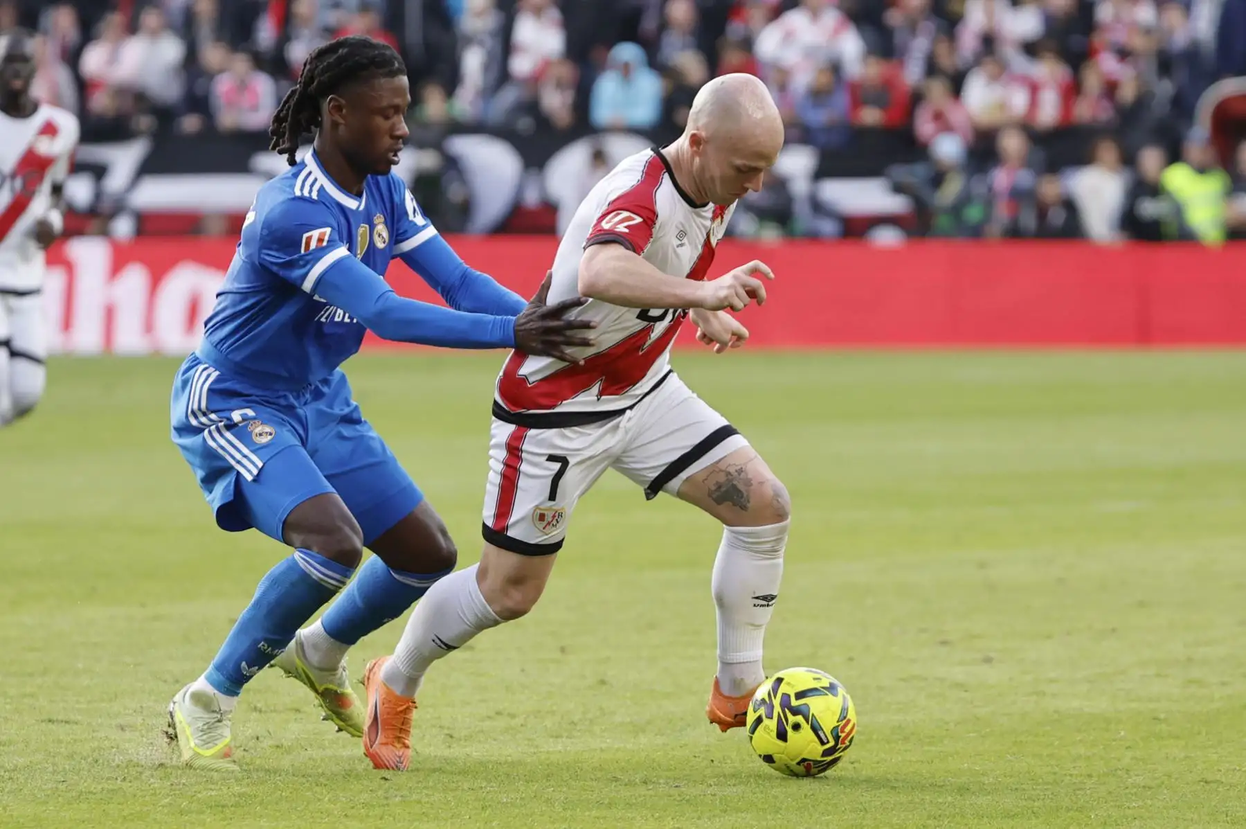 El centrocampista del Rayo Vallecano Isi Palazón pelea un balón ante el centrocampista francés del Real Madrid Eduardo Camavinga durante el partido de la jornada 12 de LaLiga EA Sports que Rayo Vallecano y Real Madrid disputan este domingo en el Estadio de Vallecas, en la capital española. Foto: EFE