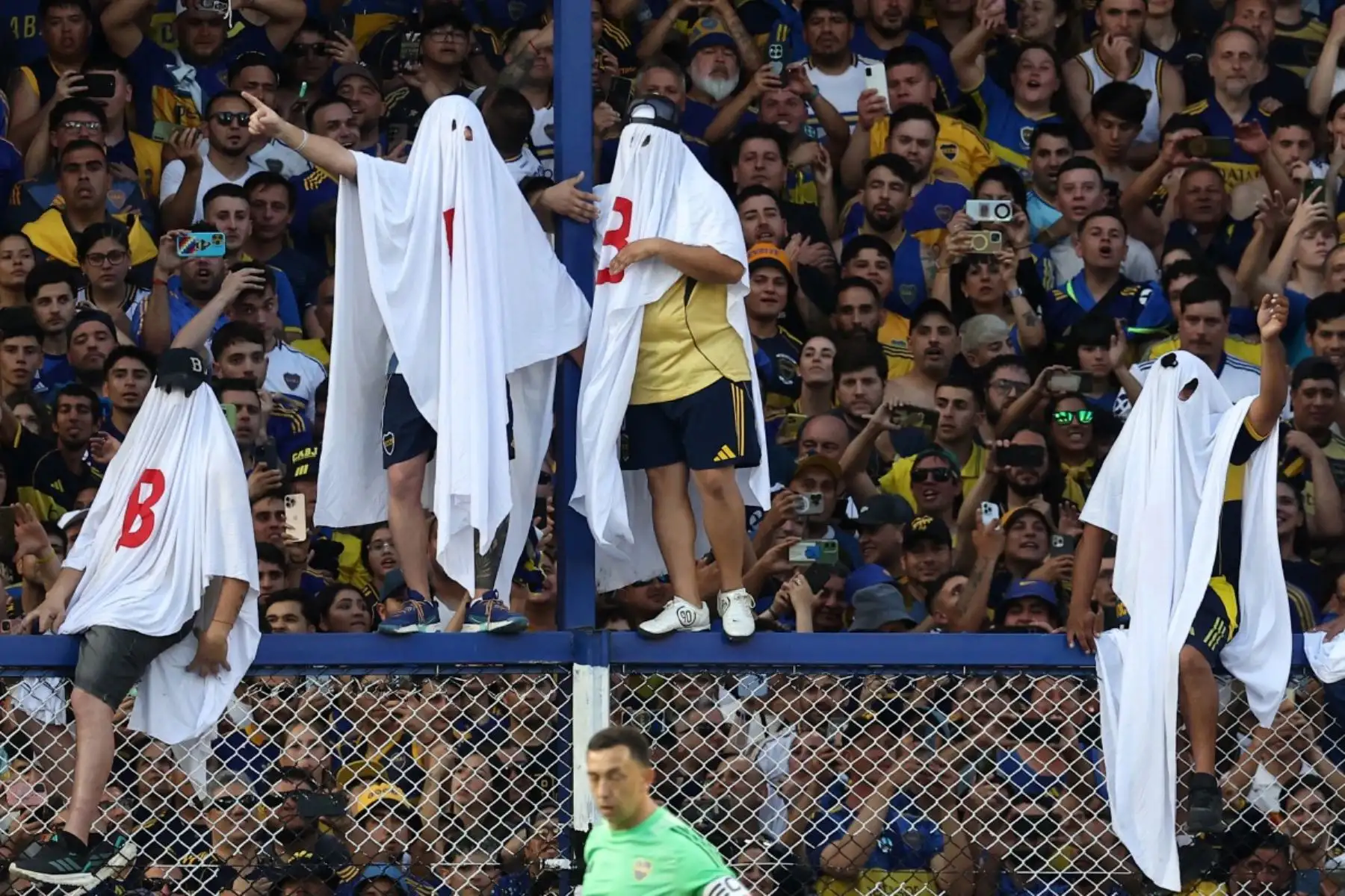 Los fanáticos de Boca Juniors vestidos de fantasmas con la letra "Bîóin en alusión al descenso del equipo argentino River Plate por su equipo durante el partido del Torneo de Clausura de la Liga Argentina de Fútbol Profesional 2025 entre Boca Juniors y River Plate en el estadio La Bombonera de Buenos Aires el 9 de noviembre de 2025. (Foto de ALEJANDRO PAGNI / AFP)