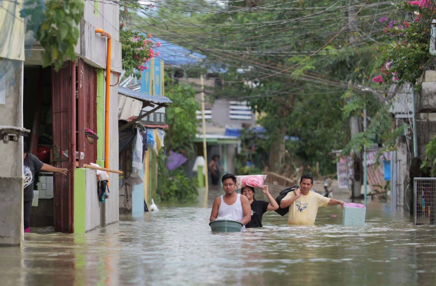 Los residentes, con sus pertenencias, vadean una calle inundada mientras evacuan a un lugar más seguro en una aldea de la ciudad de Tuguegarao, provincia de Cagayán, al norte de Manila. AFP