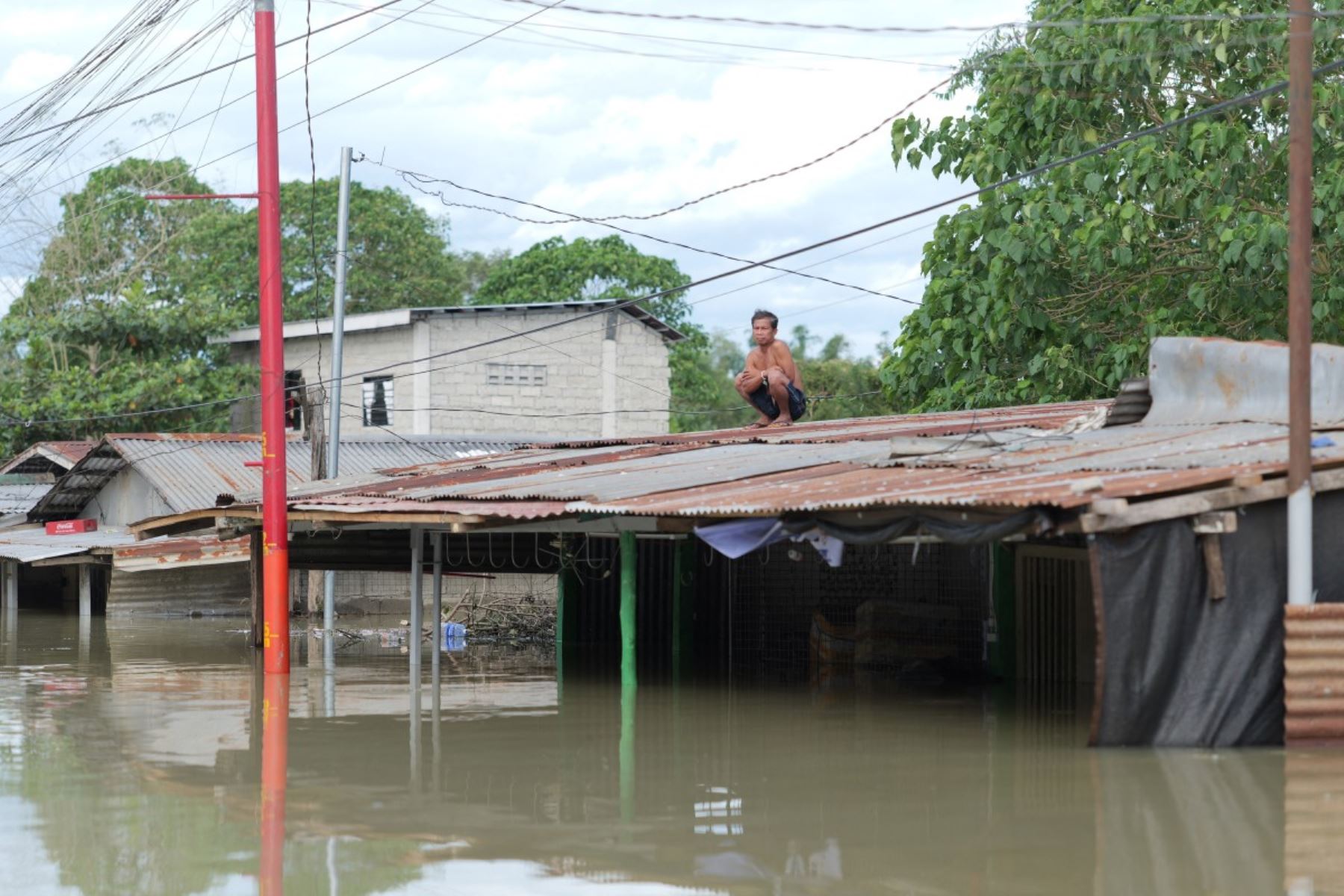 Un residente se sienta sobre el techo de su casa sumergida en una aldea de la ciudad de Tuguegarao, provincia de Cagayán, al norte de Manila. AFP