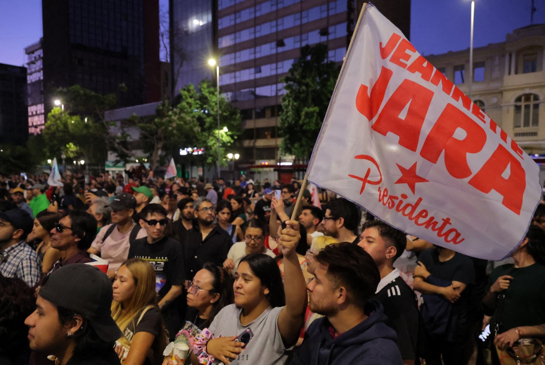 Los partidarios del candidato presidencial de Chile, Jeannette Jara, de la coalición Unidad por Chile, ondean una bandera durante un discurso después de los primeros resultados de la encuesta de salida de las elecciones generales en Santiago el 16 de noviembre de 2025. Foto: AFP