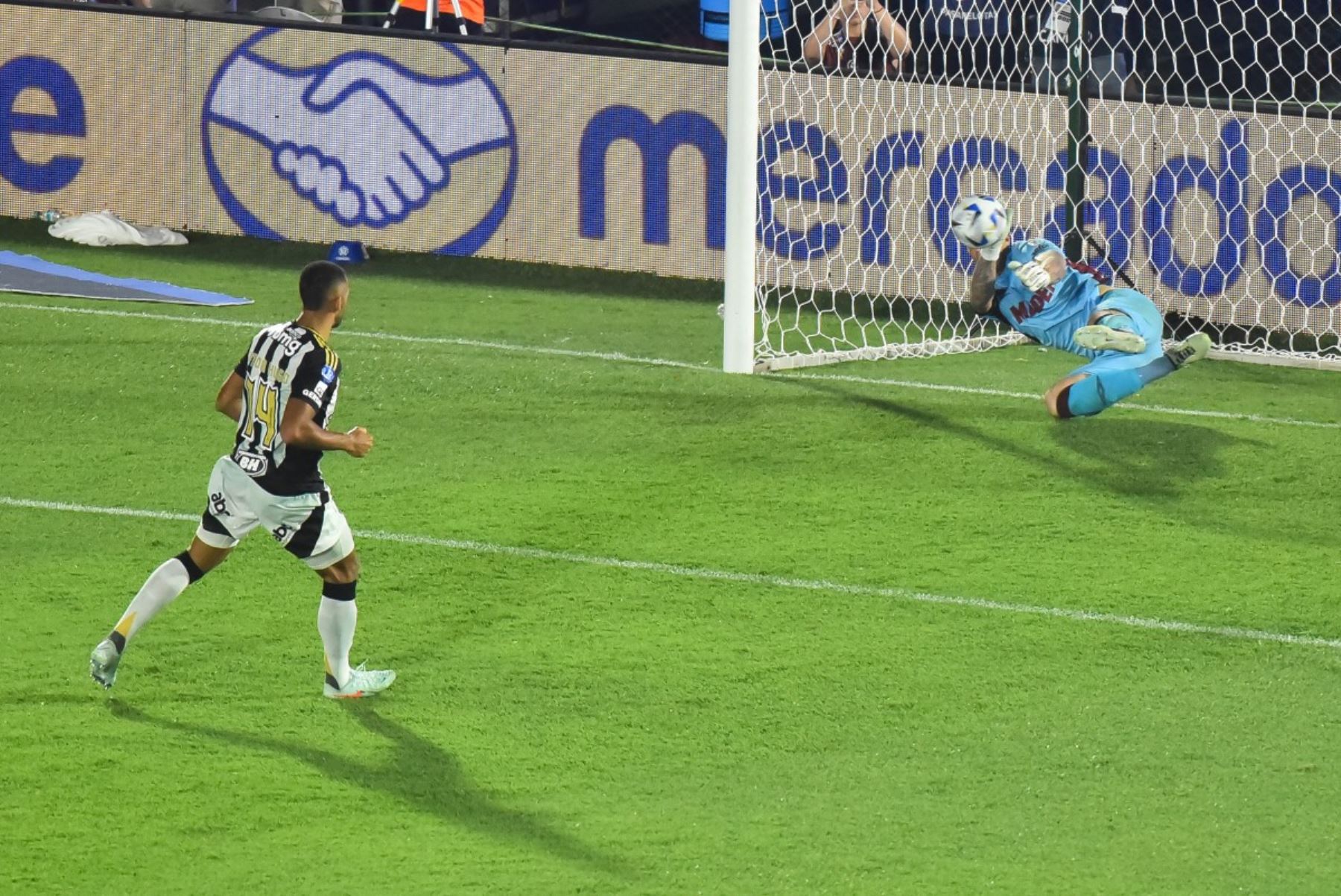 El portero #26 de Lanus, Nahuel Losada (derecha), hace una parada más allá del defensor #14 del Atlético Mineiro, Vitor Hugo (I), para ganar la tanda de penaltis del partido final de fútbol de la Copa Sudamericana entre el argentino Lanus y el Atlético Mineiro de Brasil en el estadio Defensores del Chaco en Asunción el 22 de noviembre de 2025. (Foto de JOSE BOGADO / AFP)