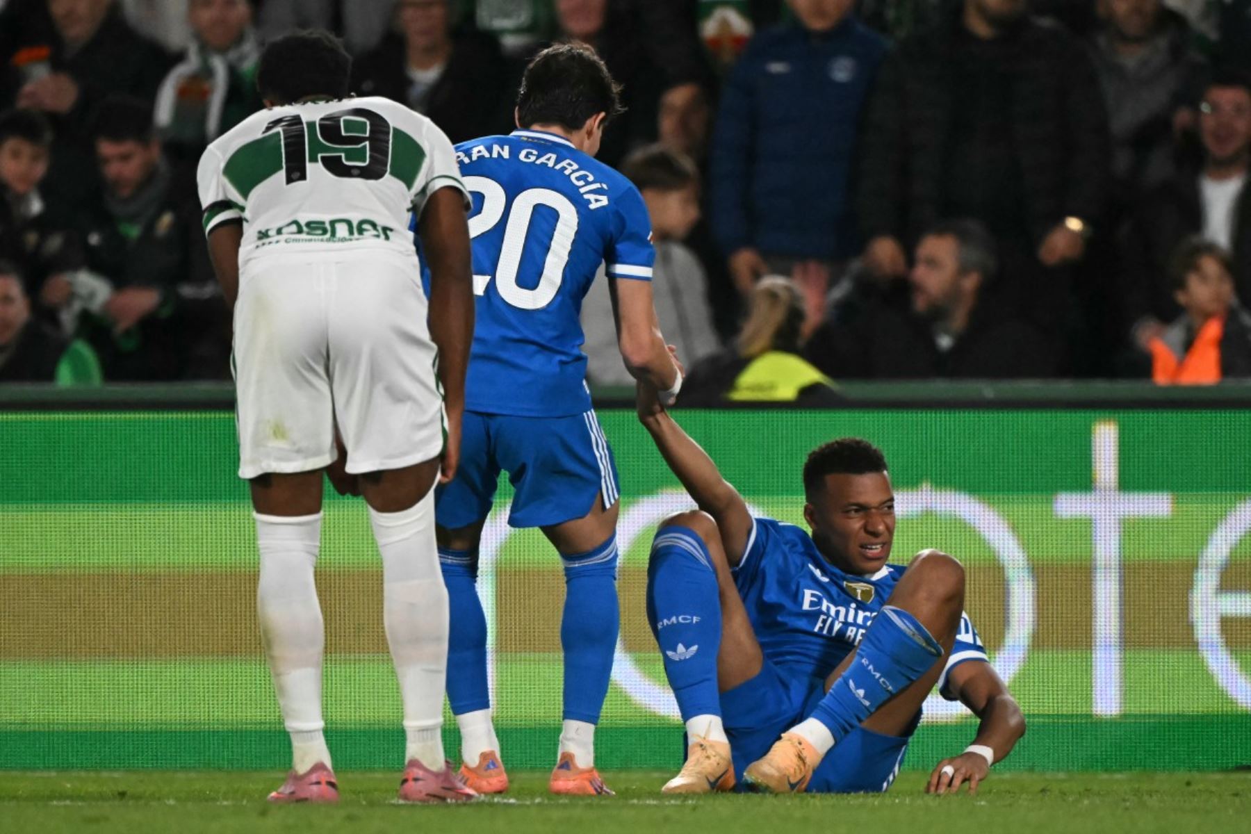 El defensor español #20 del Real Madrid, Francisco García, ayuda al delantero francés del Real Madrid #10 Kylian Mbappe a ponerse de pie durante el partido de fútbol de la liga española entre Elche CF y Real Madrid CF en el Estadio Martínez Valero en Elche el 23 de noviembre de 2025. (Foto de JOSE JORDAN / AFP)