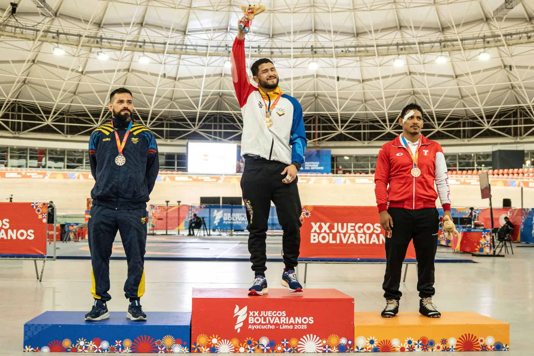 Los luchadores Luis Avendaño de Venezuela, medalla de oro, Carlos Andrés Muñoz de Colombia, medalla de plata y Carlos Espinoza de perú, medalla de bronce, celebran en el podio este domingo, al finalizar la lucha grecorromana en los vigésimos Juegos Bolivarianos en la Villa Deportiva Nacional en Lima (Perú). Foto: ANDINA/EFE
