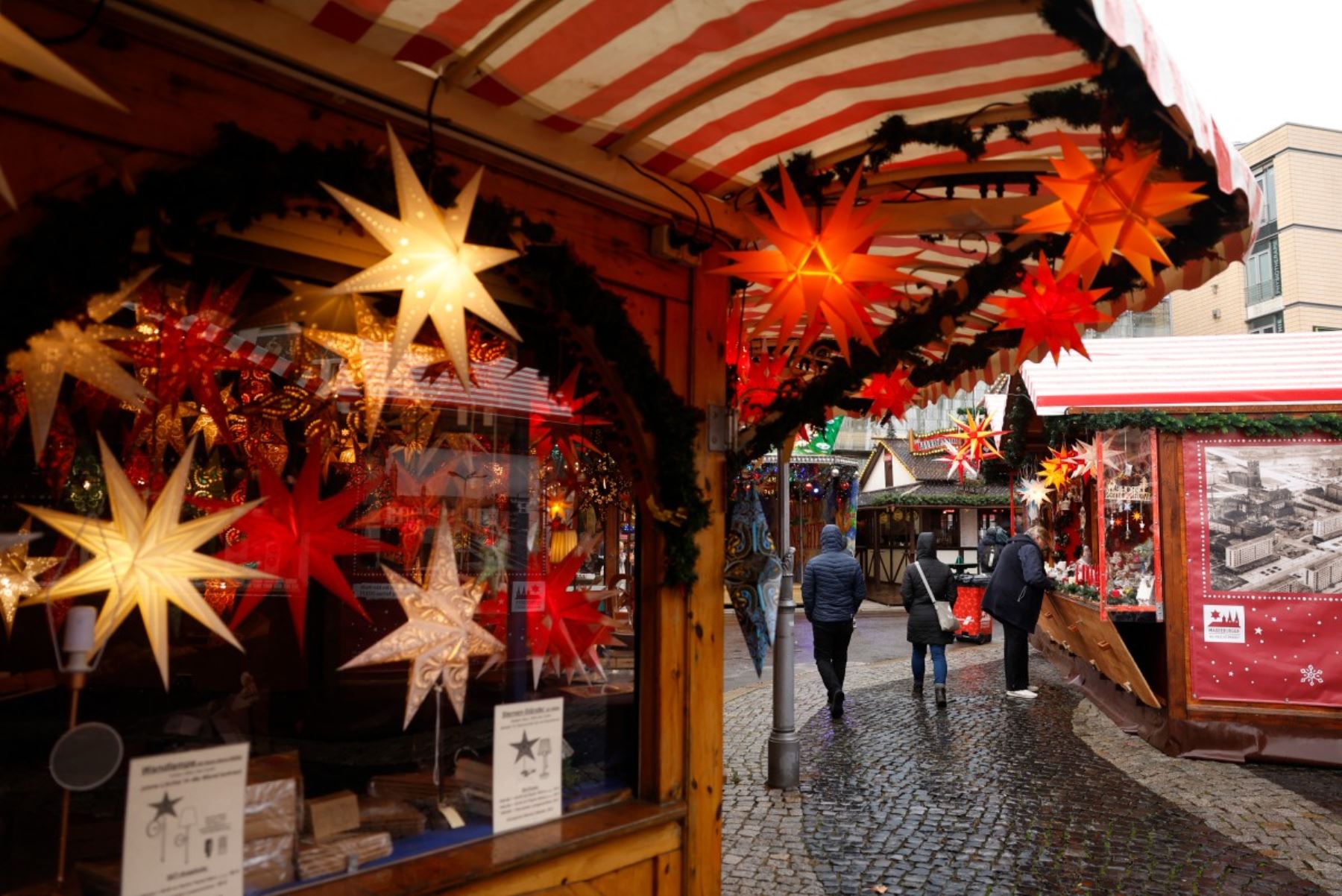 La gente pasea entre puestos con estrellas navideñas colgando de las vitrinas del mercado navideño durante su "apertura silenciosa" en la Plaza del Mercado Viejo de Magdeburgo, este de Alemania. AFP