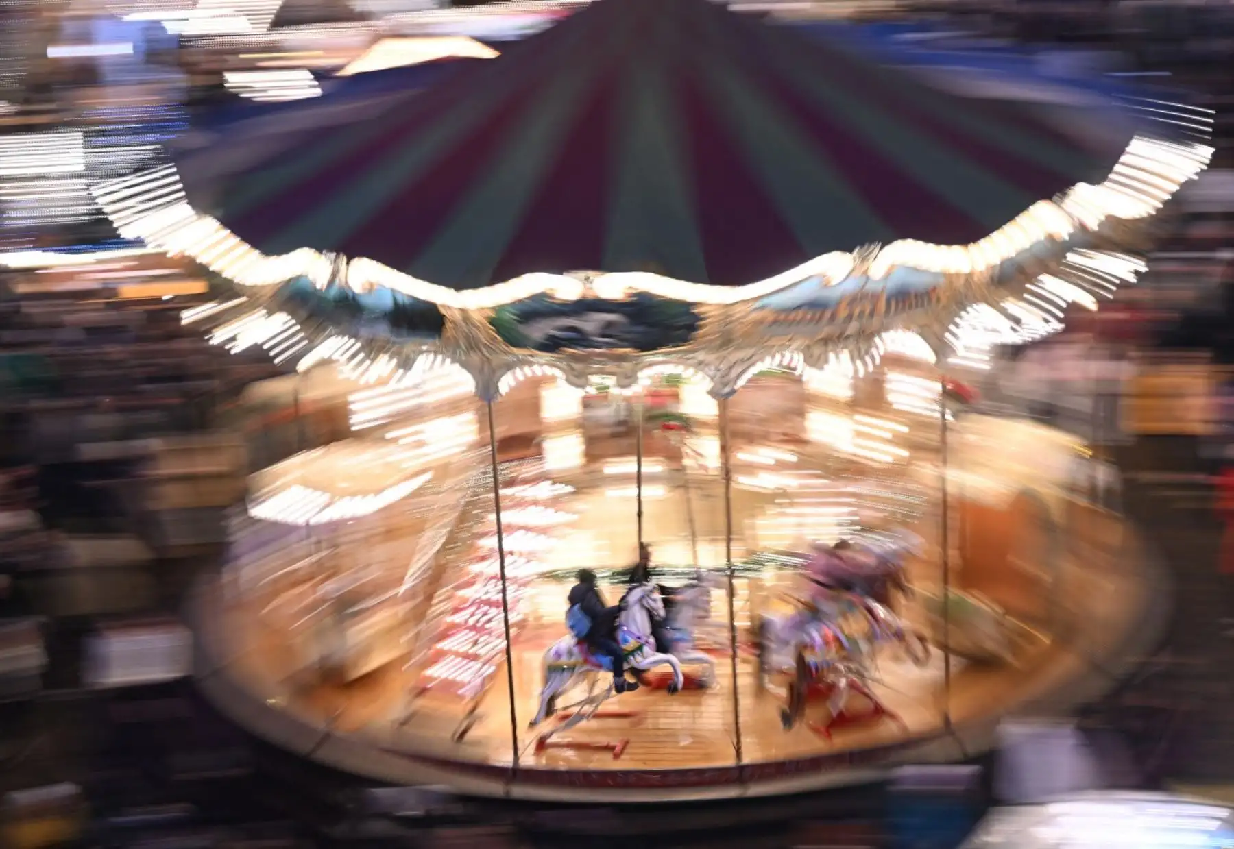 La gente se sienta en un tiovivo en el mercado navideño de la céntrica plaza Roemer de Frankfurt am Main. AFP