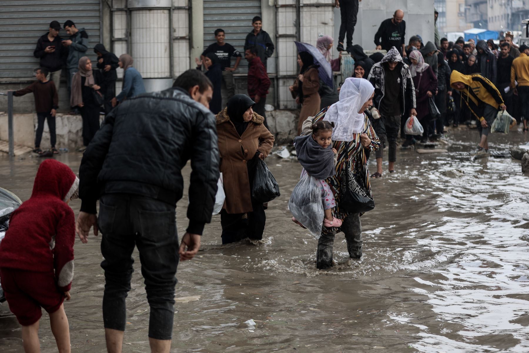 Personas caminan entre las aguas inundadas en un campamento improvisado que alberga a palestinos desplazados tras las fuertes lluvias en la ciudad de Gaza el 25 de noviembre de 2025. La Franja de Gaza ha quedado prácticamente reducida a escombros tras dos años de combates. Foto: AFP