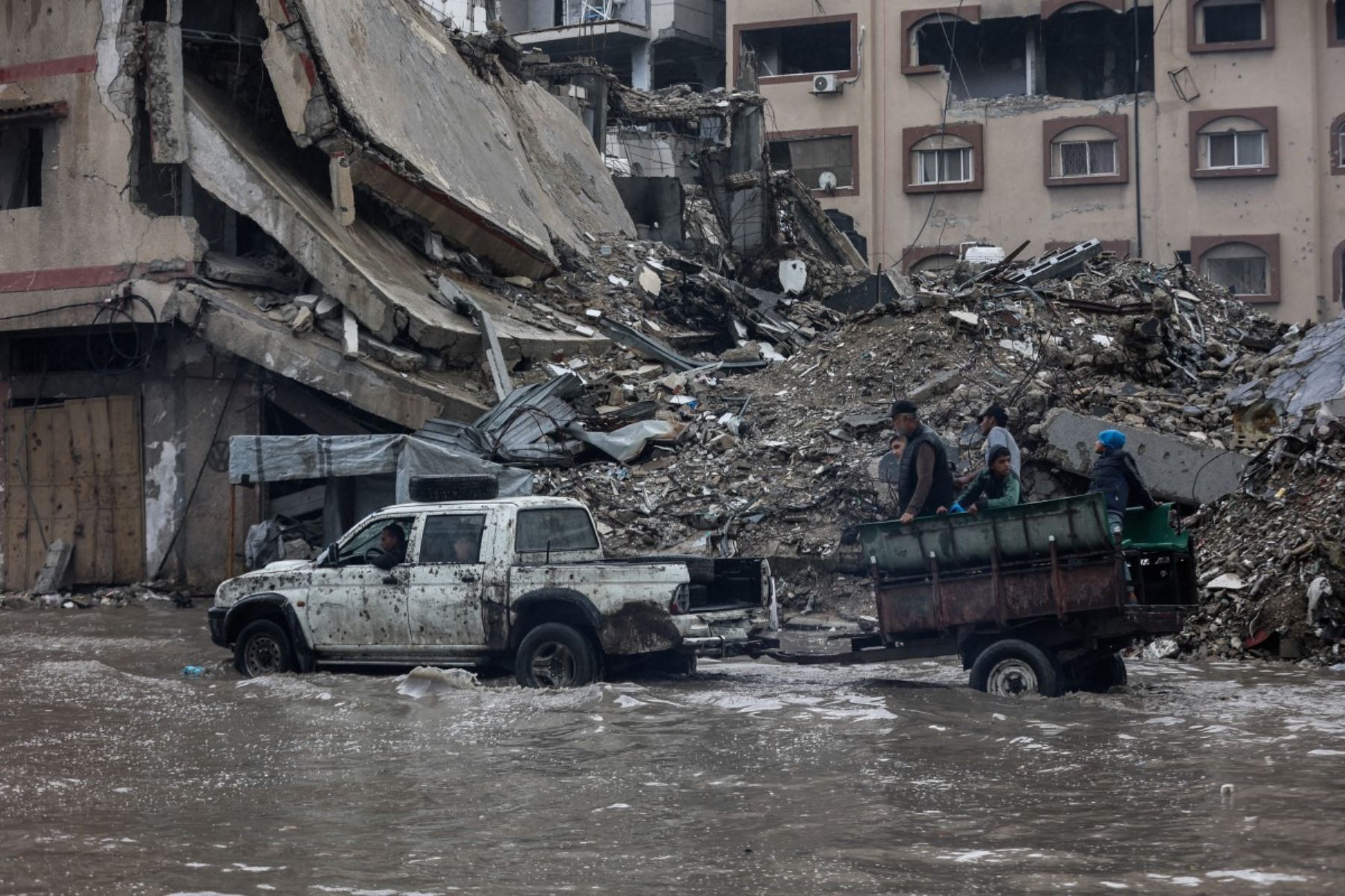 Personas viajan en un carro tirado por un automóvil que avanza a través de las aguas inundadas en un campamento improvisado que alberga a palestinos desplazados tras las fuertes lluvias en la ciudad de Gaza el 25 de noviembre de 2025. Foto: AFP