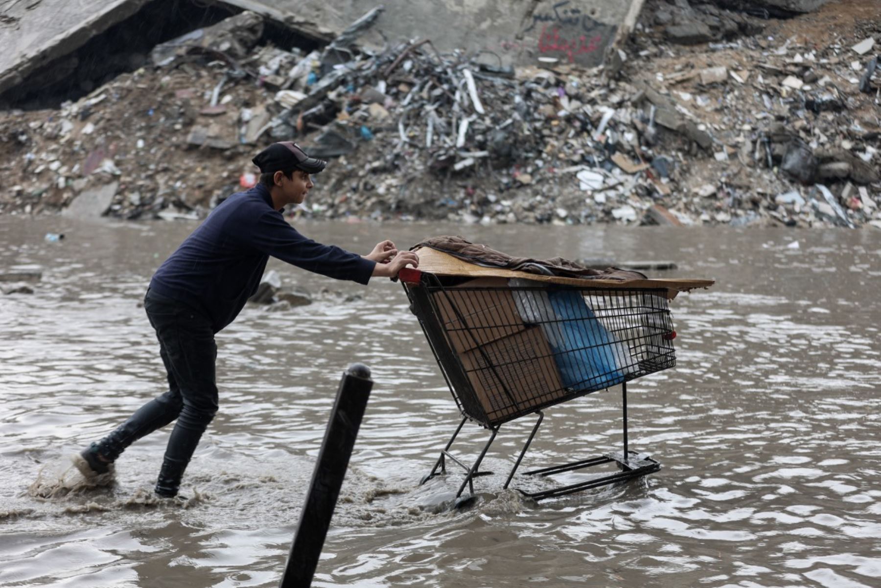 Un hombre empuja una carretilla en medio de las inundaciones en un campamento improvisado que alberga a palestinos desplazados tras las fuertes lluvias en la ciudad de Gaza el 25 de noviembre de 2025. La Franja de Gaza ha quedado prácticamente reducida a escombros tras dos años de combates. Foto: AFP