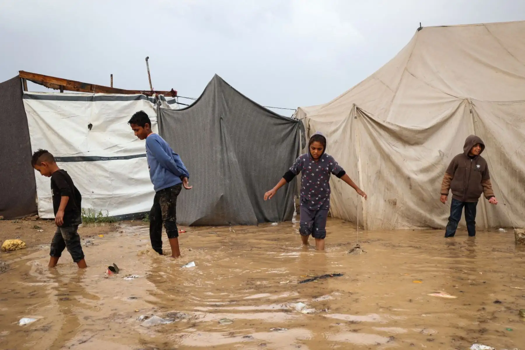 Niños palestinos caminan entre las aguas después de que fuertes lluvias inundaran un campamento improvisado que albergaba a personas desplazadas en el campo de refugiados de Maghazi, en el centro de la Franja de Gaza, el 25 de noviembre de 2025. Foto: AFP