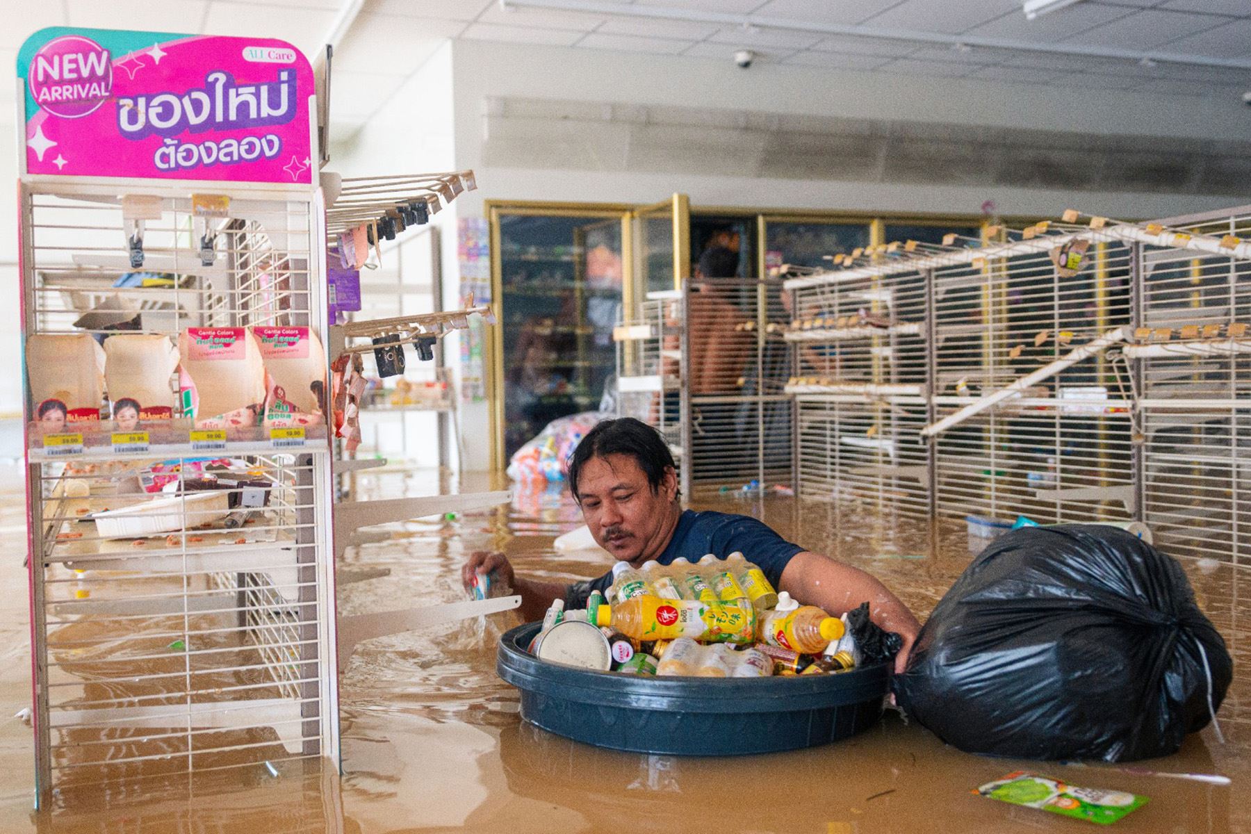 Un hombre empuja un contenedor lleno de bebidas mientras camina por el agua en una tienda 7/11 inundada en Hat Yai, en la provincia sureña tailandesa de Songkhla. Foto: AFP
