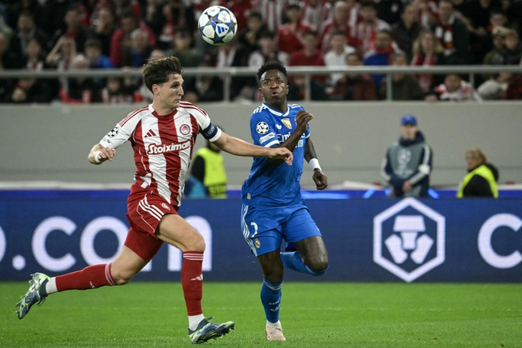 El defensa griego  del Olympiakos, Panagiotis Retsos  lucha por el balón con el delantero brasileño  del Real Madrid, Vinicius Junior, durante la quinta jornada de la fase de liga de la UEFA Champions League, partido de fútbol entre el Olympiakos y el Real Madrid. AFP