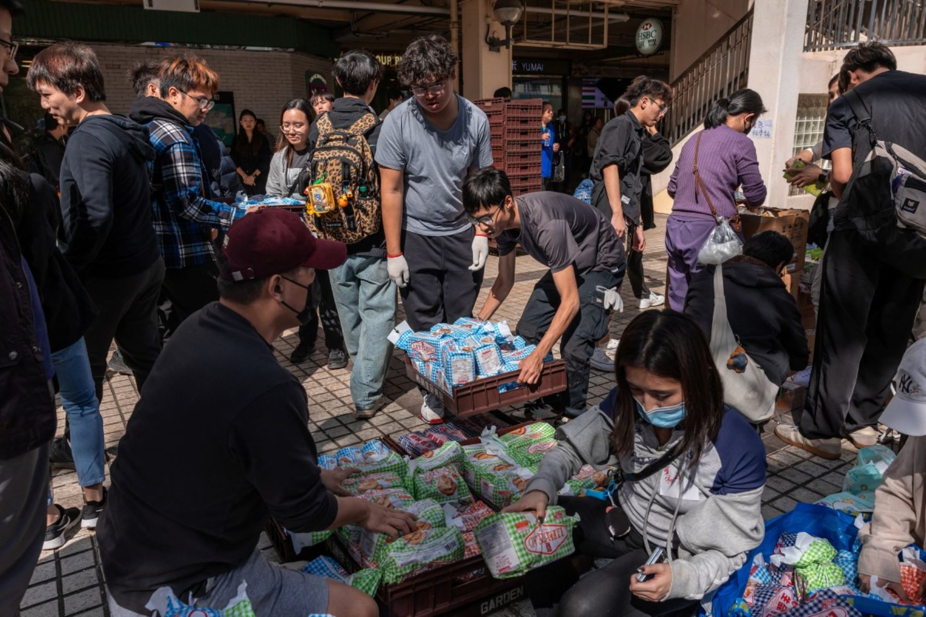 Voluntarios distribuyen pan para los residentes cerca de la escena de un gran incendio que arrasó varios bloques de apartamentos en el complejo residencial Wang Fuk Court, en el distrito Tai Po de Hong Kong. AFP