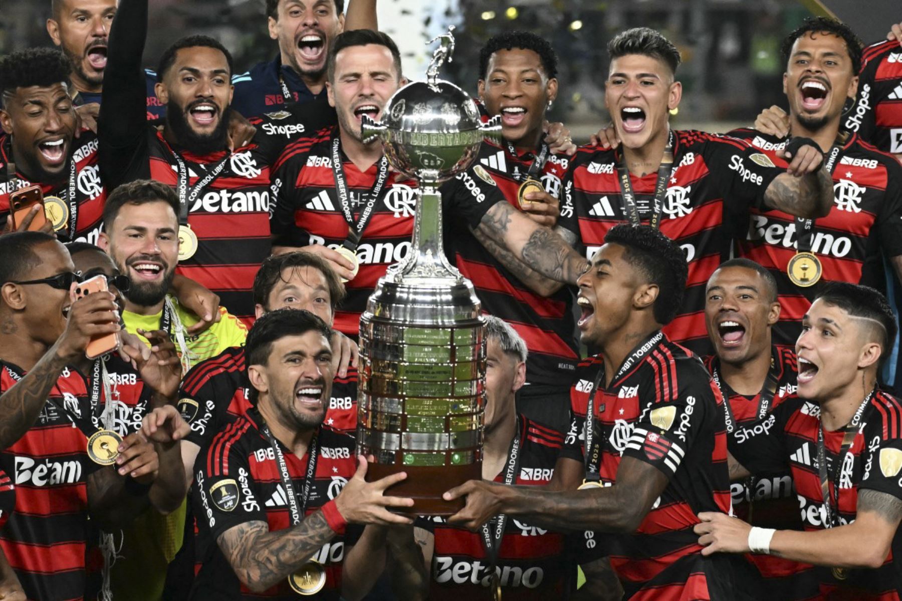 El delantero del Flamengo #27 Bruno Henrique (R) y el centrocampista uruguayo #10 Giorgian de Arrascaeta (L) levantan el trofeo con sus compañeros de equipo después de ganar el partido final de fútbol de la Copa Libertadores brasileña entre Palmeiras y Flamengo en el estadio Monumental 