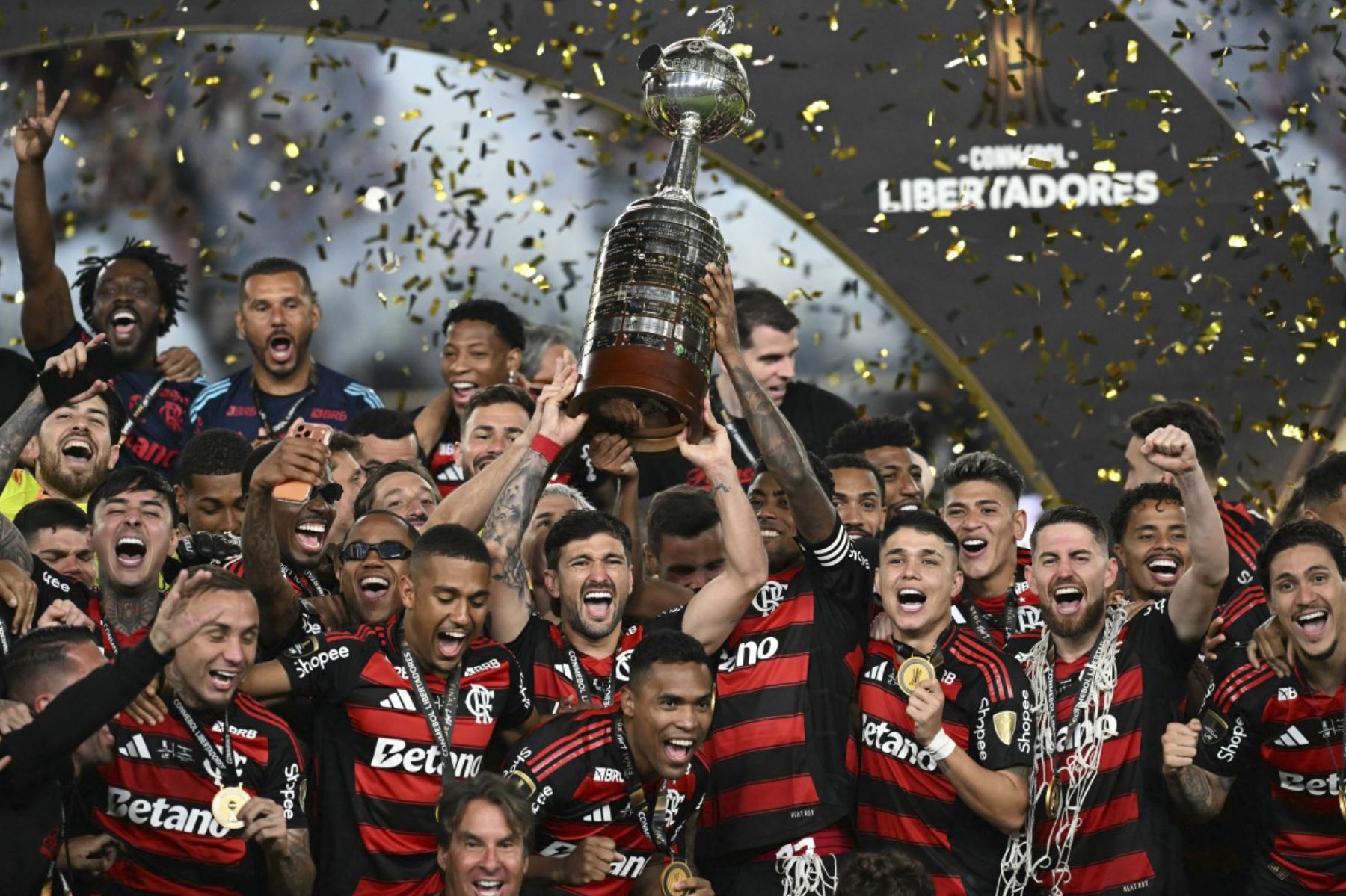 El delantero del Flamengo #27 Bruno Henrique (R) y el centrocampista uruguayo #10 Giorgian de Arrascaeta (L) levantan el trofeo con sus compañeros de equipo después de ganar el partido final de fútbol de la Copa Libertadores brasileña entre Palmeiras y Flamengo en el estadio Monumental 