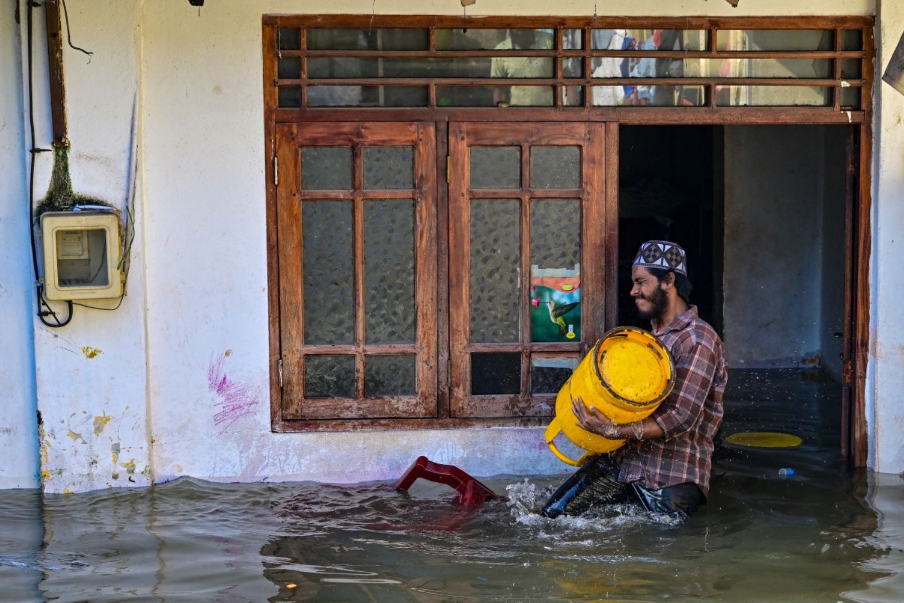Un hombre lleva un tanque de gas afuera de su casa inundada en Wellampitiya, en las afueras de Colombo. AFP