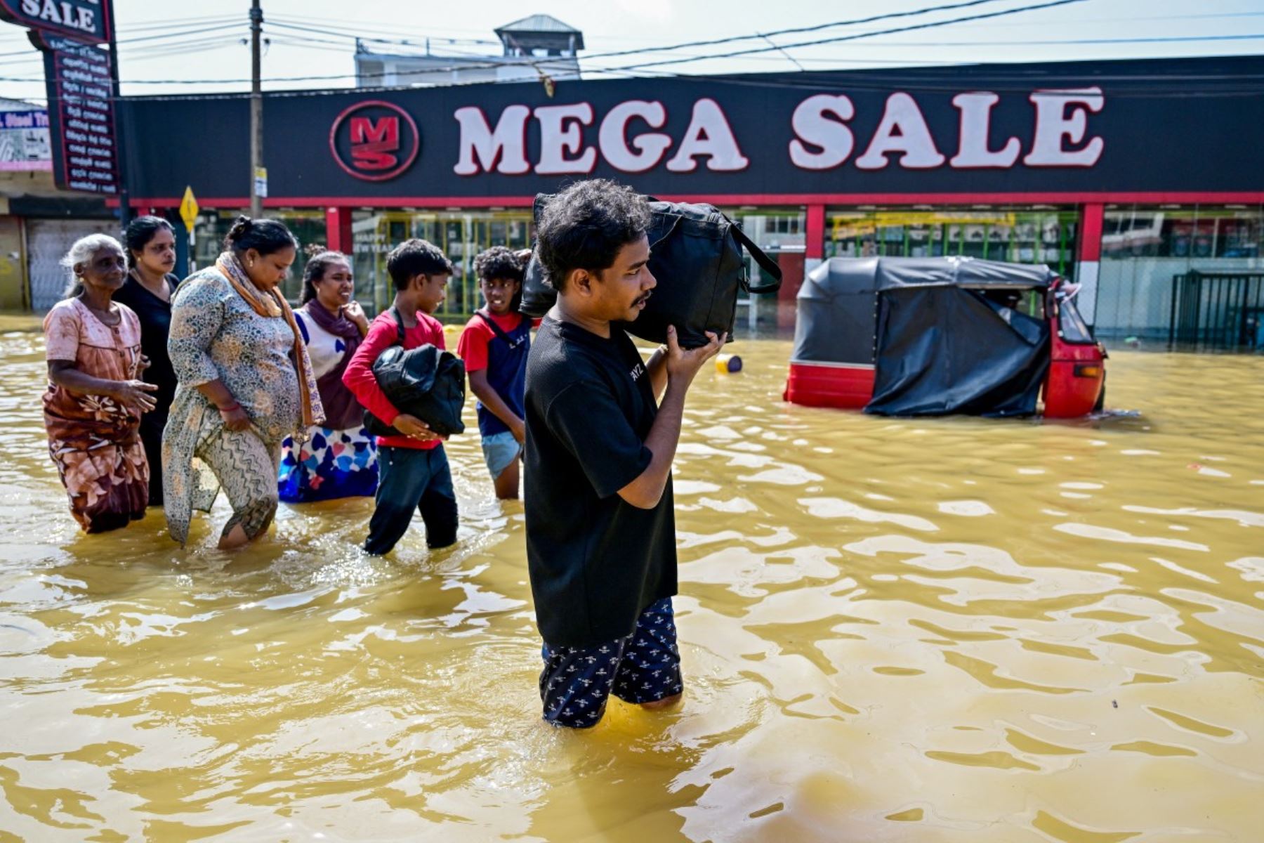Personas con sus pertenencias caminan por una calle inundada después de fuertes lluvias en Wellampitiya, en las afueras de Colombo. AFP