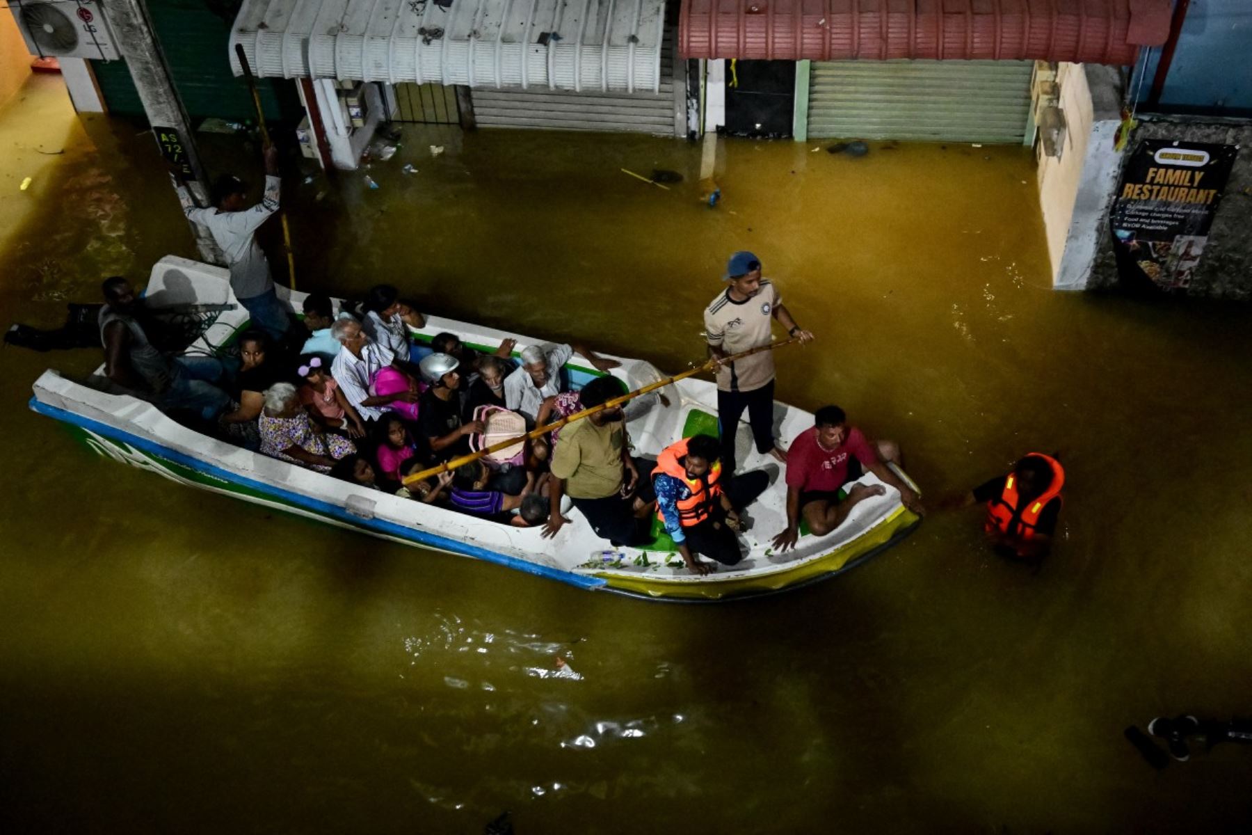 La gente viaja en un barco perteneciente al ejército de Sri Lanka en una calle inundada después de fuertes lluvias en Wellampitiya, en las afueras de Colombo. AFP