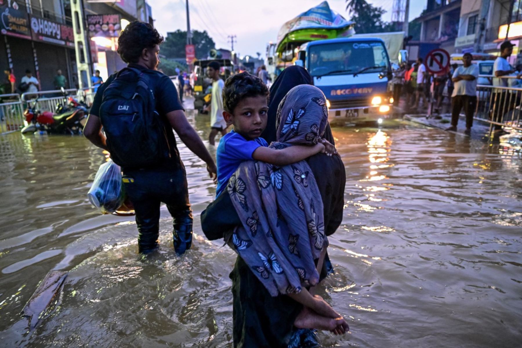 Una mujer con un niño camina por una calle inundada tras las fuertes lluvias en Wellampitiya, en las afueras de Colombo. AFP