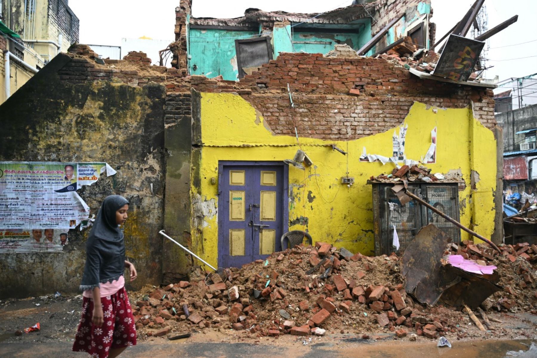Una niña pasa junto a un edificio que se derrumbó debido al ciclón Ditwah, en Chennai. AFP