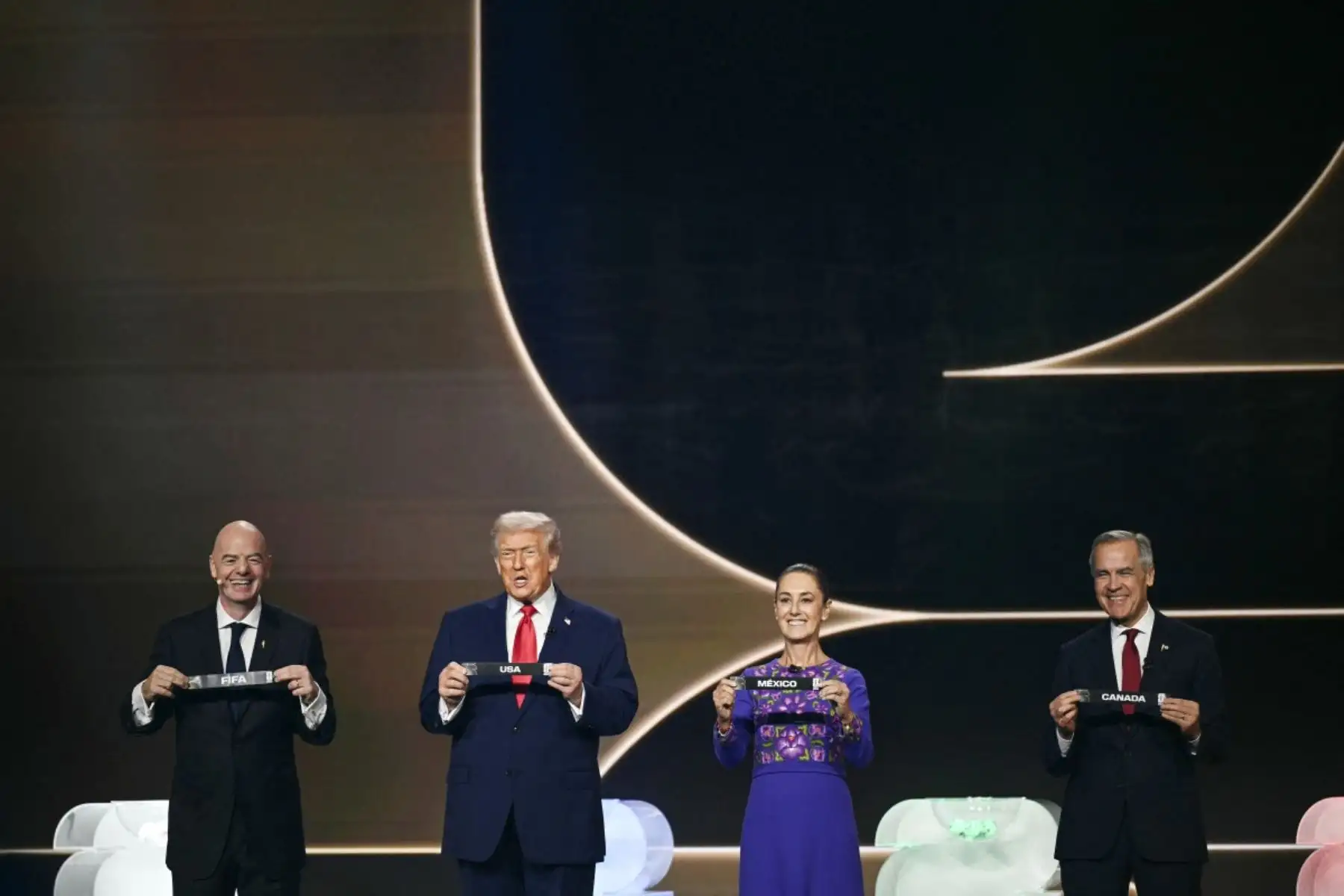 El presidente de la FIFA, Gianni Infantino, el presidente de Estados Unidos, Donald Trump, la presidenta de México, Claudia Sheinbaum, y el primer ministro de Canadá, Mark Carney, sostienen tarjetas en el escenario durante el sorteo de la Copa Mundial de Fútbol de la FIFA 2026 que se lleva a cabo en Estados Unidos, Canadá y México, en el Kennedy Center, en Washington, DC. AFP