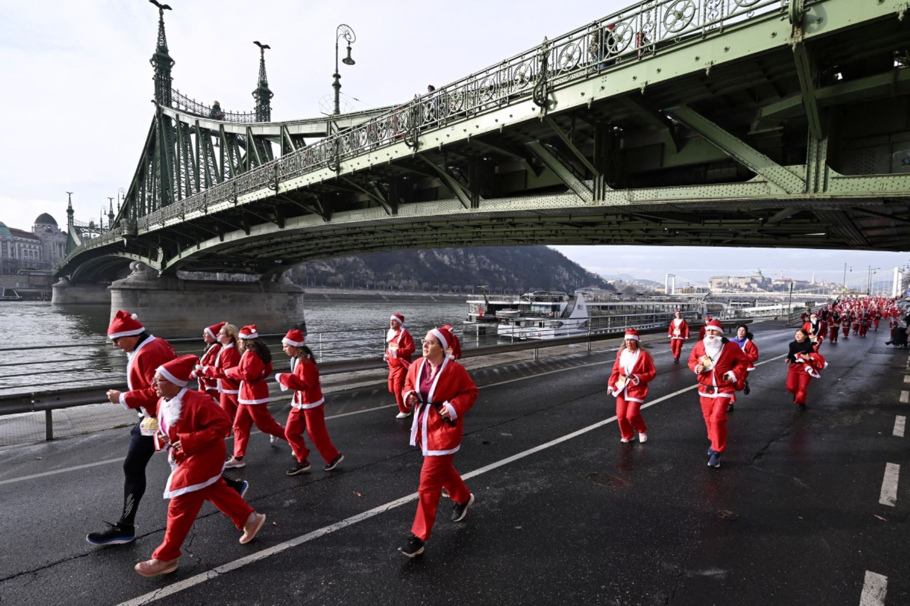 Ciudadanos con disfraces de Papá Noel participan en la tradicional carrera de Papá Noel a lo largo del río Danubio en Budapest, Hungría, el 7 de diciembre de 2025. Alrededor de cinco mil participantes participaron en la carrera para tres categorías: familias con niños, aficionados y corredores profesionales. (Foto de Attila KISBENEDEK / AFP)