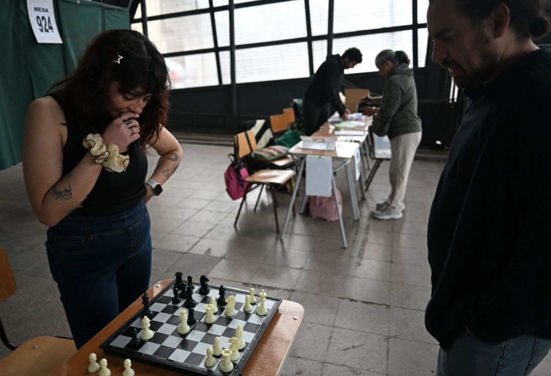 Los miembros del personal electoral juegan al ajedrez en un colegio electoral durante la segunda temporada de las elecciones presidenciales en la estación de Mapocho en Santiago el 14 de diciembre de 2025. Los chilenos se dirigen a las urnas para una resección presidencial entre Jeannette Jara, una comunista respaldada por una amplia coalición de izquierda, y José Antonio Kast, un devoto político de extrema derecha que promete una línea dura en seguridad y migración. (Foto de Eitan ABRAMOVICH / AFP)