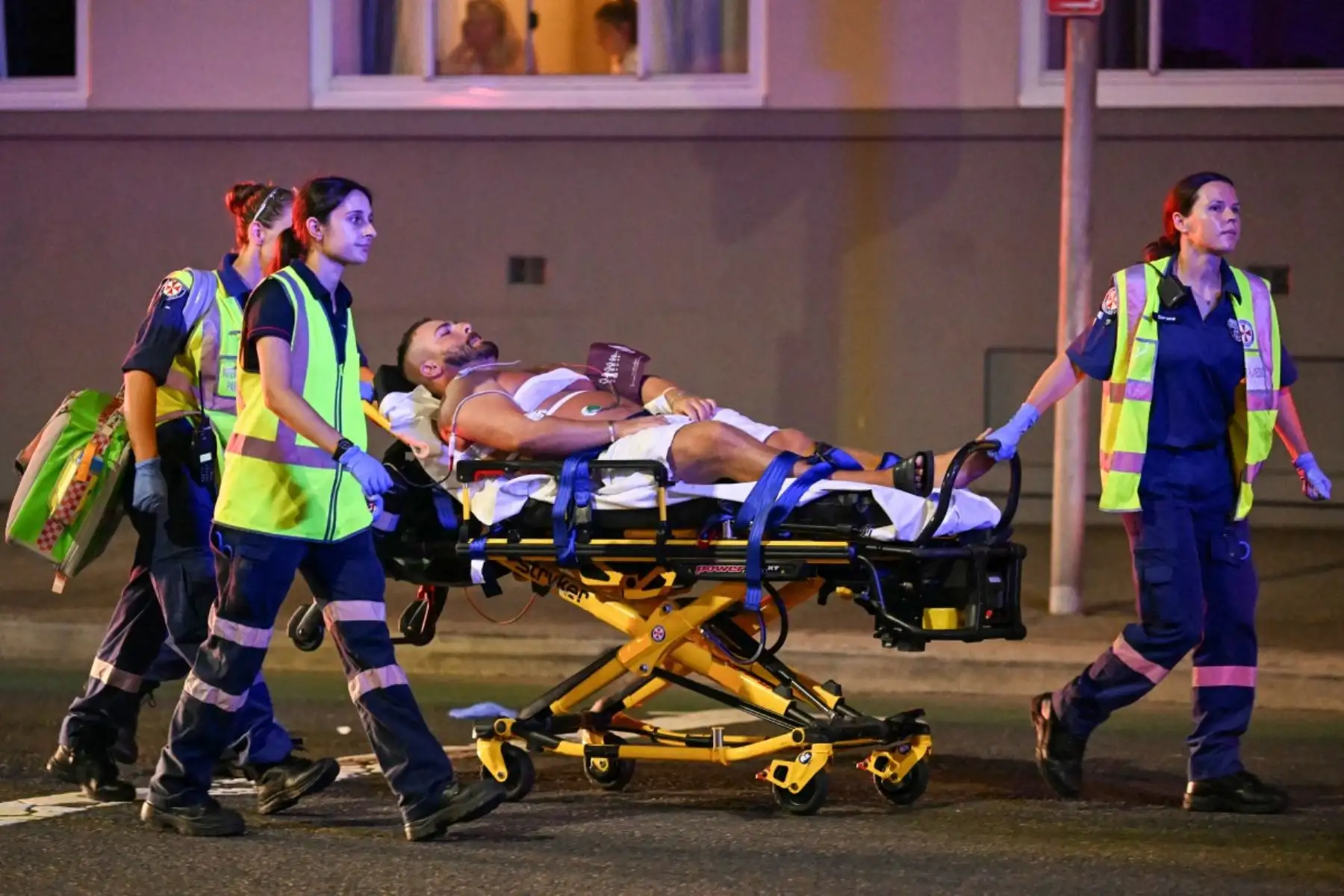 Paramédicos trasladan a un hombre en una camilla a una ambulancia después de un tiroteo en Bondi Beach en Sydney el 14 de diciembre de 2025. La policía australiana dijo que dos personas estaban bajo custodia después de informes de múltiples disparos el 14 de diciembre en la famosa playa Bondi de Sydney, instando al público a refugiarse. (Foto de Saeed KHAN / AFP)