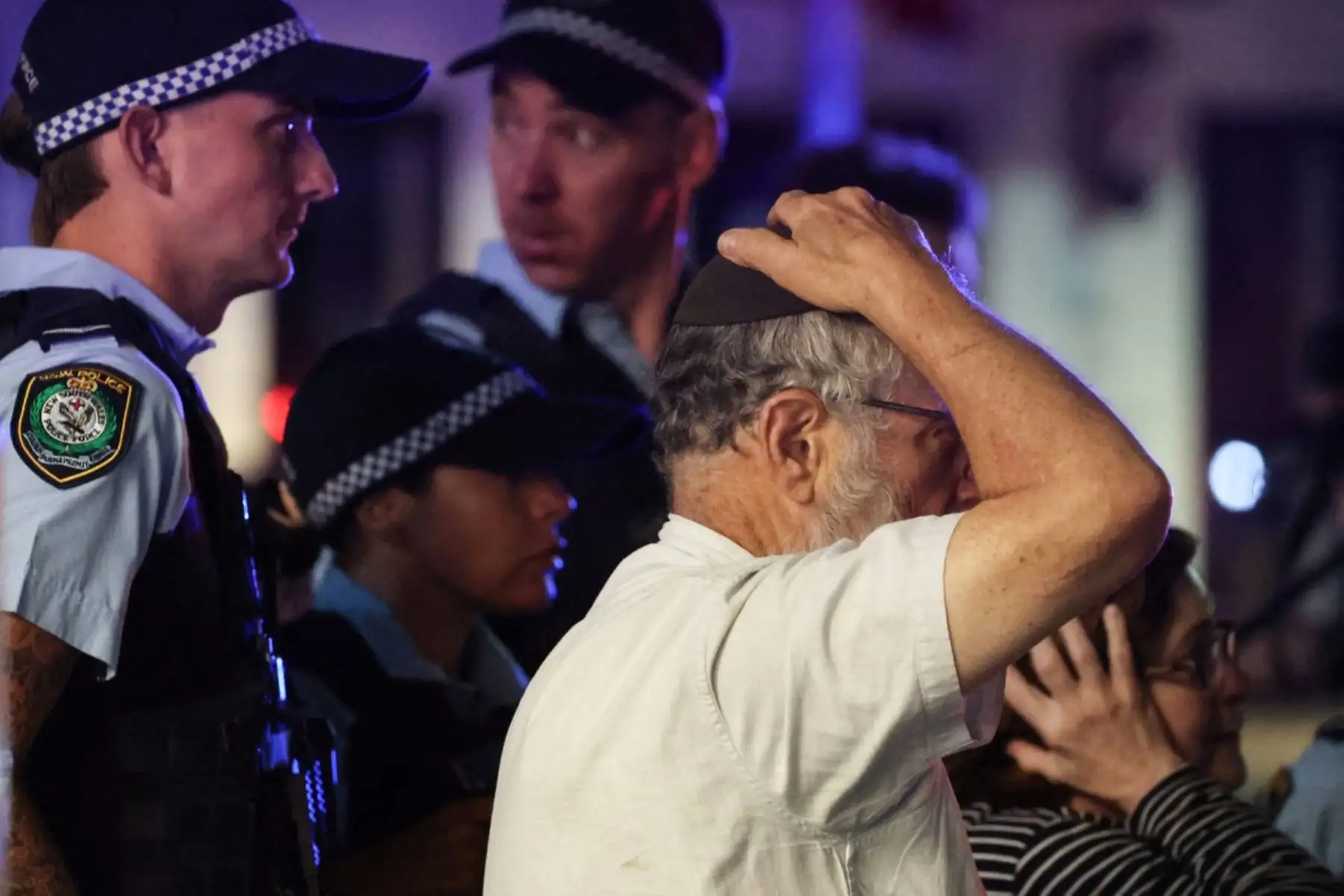 Un miembro de la comunidad judía reacciona mientras camina con la policía hacia la escena de un tiroteo en Bondi Beach en Sydney el 14 de diciembre de 2025. La policía australiana dijo que dos personas estaban bajo custodia después de informes de múltiples disparos el 14 de diciembre en la famosa playa Bondi de Sydney, instando al público a refugiarse. (Foto de DAVID GRAY / AFP)