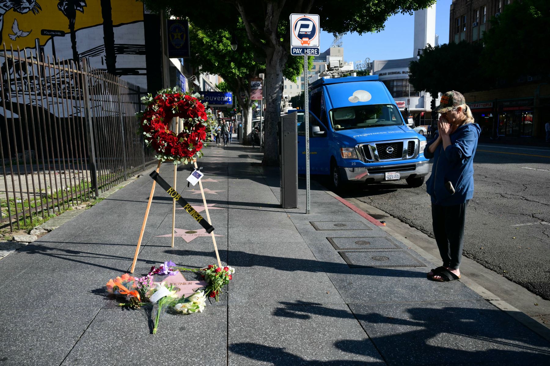 Una mujer reza frente a la estrella del actor y director estadounidense Rob Reiner en el Paseo de la Fama de Hollywood, en Los Ángeles, California, el 15 de diciembre de 2025, quien fue hallado muerto en su mansión junto a su esposa. Foto: AFP