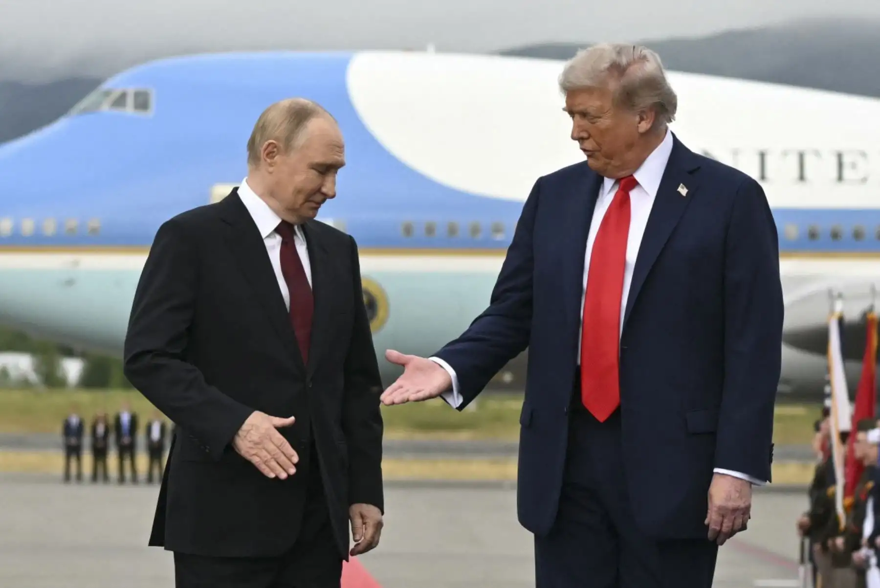 El presidente estadounidense Donald Trump se acerca para estrechar la mano del presidente ruso Vladimir Putin mientras posan en un podio en la pista después de llegar a la Base Conjunta Elmendorf-Richardson en Anchorage, Alaska, el 15 de agosto de 2025. (Foto de ANDREW CABALLERO-REYNOLDS / AFP)