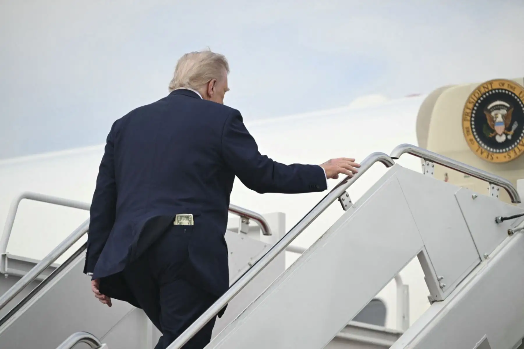 Se ve un billete de cincuenta dólares en el bolsillo trasero del presidente de los Estados Unidos, Donald Trump, mientras aborda el Air Force One antes de partir de la Base Conjunta Andrews en Maryland, el 1 de mayo de 2025, mientras viaja a Alabama para dar un discurso de graduación antes de pasar el fin de semana en Florida. (Foto de SAUL LOEB / AFP)