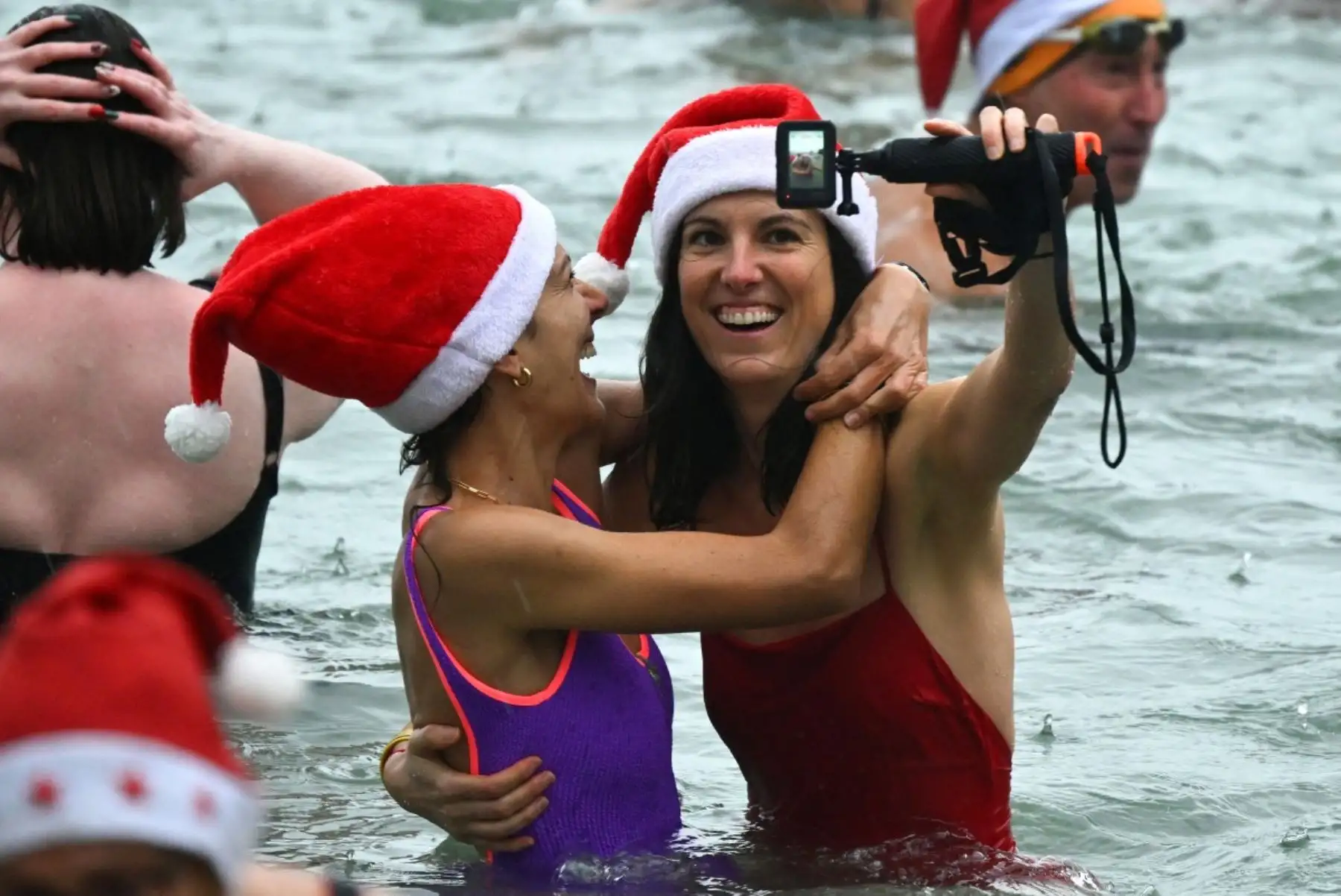 Bañistas vestidos de Papá Noel y otros con gorros navideños participan en el tradicional baño navideño en Niza, en la Riviera Francesa.
Foto: AFP
