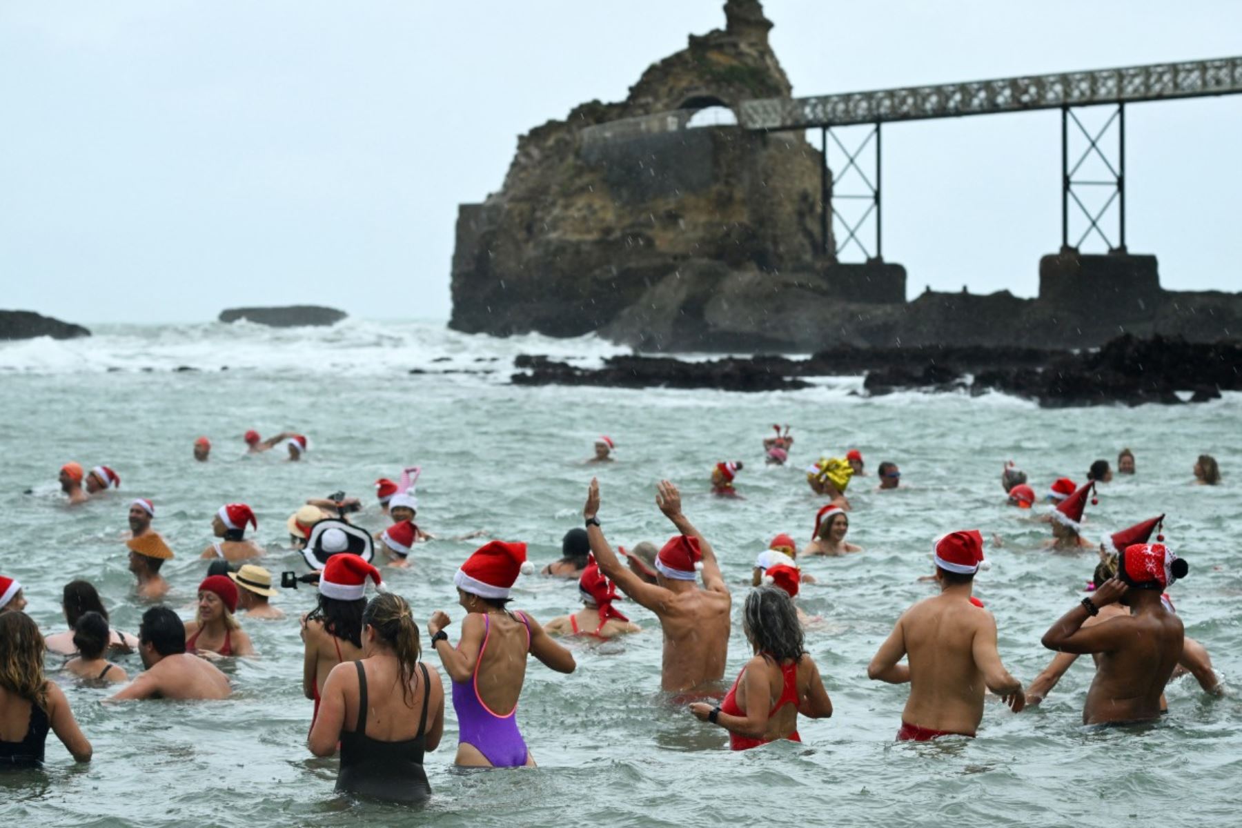 Bañistas vestidos de Papá Noel y otros con gorros navideños participan en el tradicional baño navideño en Niza, en la Riviera Francesa.
Foto: AFP