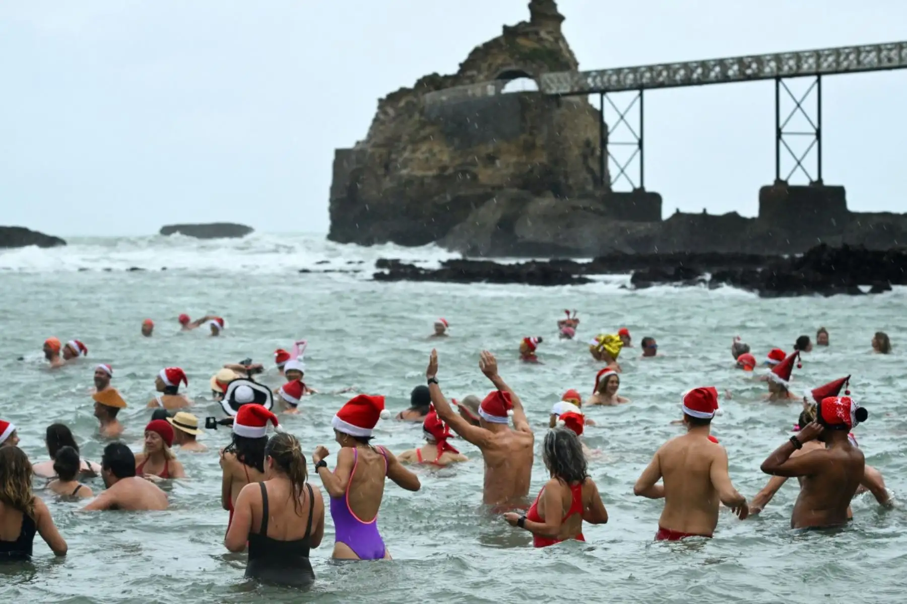 Bañistas vestidos de Papá Noel y otros con gorros navideños participan en el tradicional baño navideño en Niza, en la Riviera Francesa.
Foto: AFP