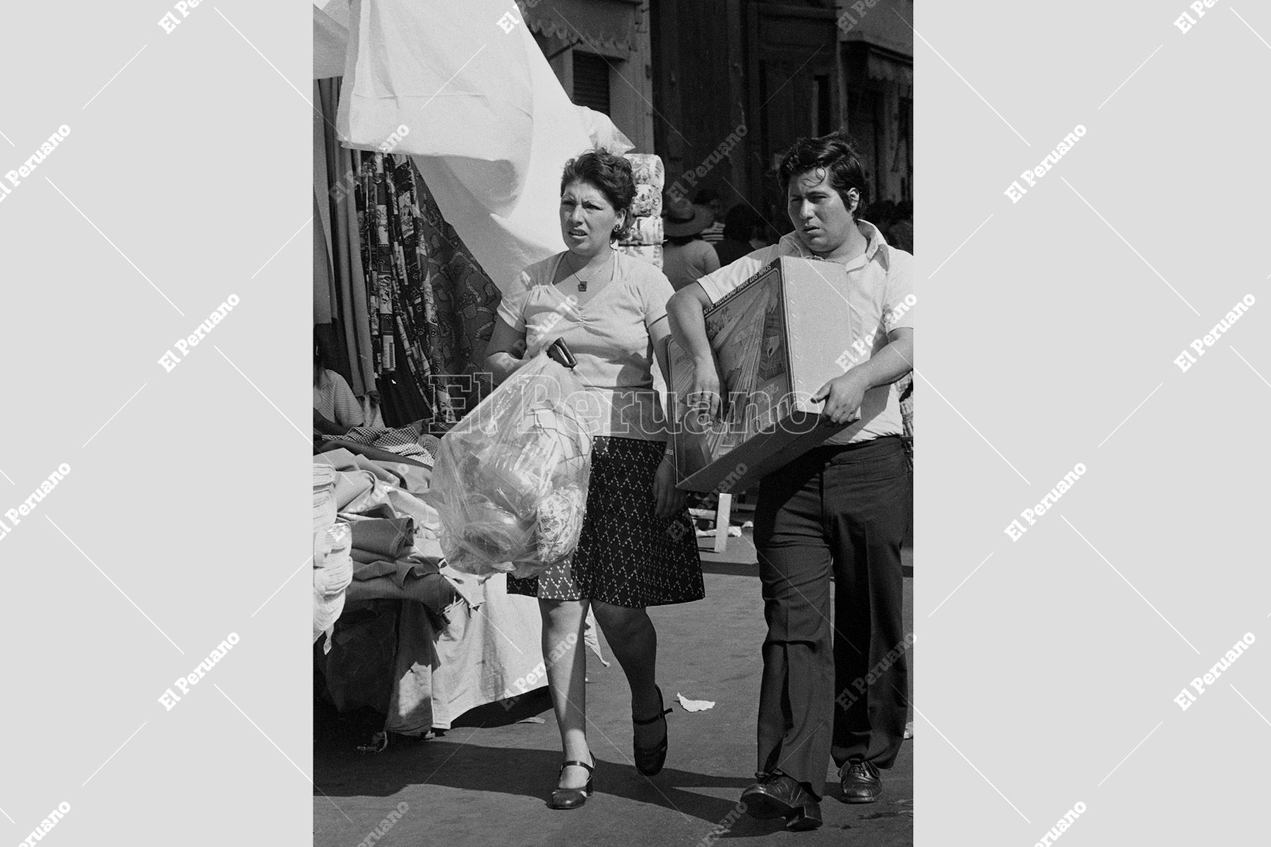Lima – 19 diciembre 1977 / Una pareja avanza entre bolsos y regalos en plena jornada de compras, reflejo del intenso movimiento comercial y del espíritu festivo que se apodera de la ciudad a pocos días de Navidad. Foto: Archivo Histórico de El Peruano / Norman Córdova