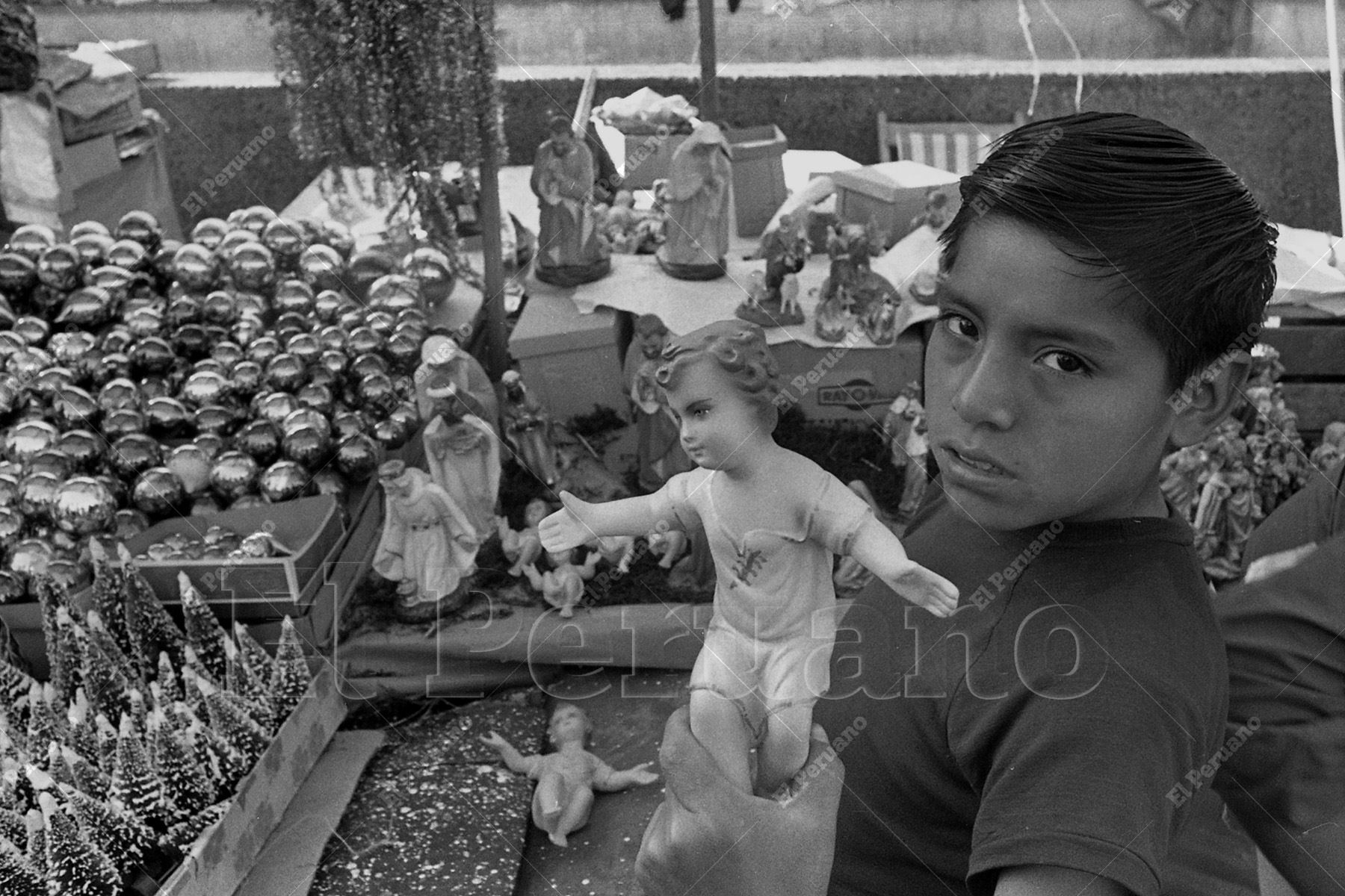 Lima – 14  diciembre 1974 / Un niño muestra la imagen del Niño Jesús, en medio de la venta de nacimientos y otras estampas tradicionales que, en vísperas de la Navidad, forman parte del paisaje urbano y de las costumbres familiares. Foto: Archivo Histórico de El Peruano / Carlos Domínguez.
