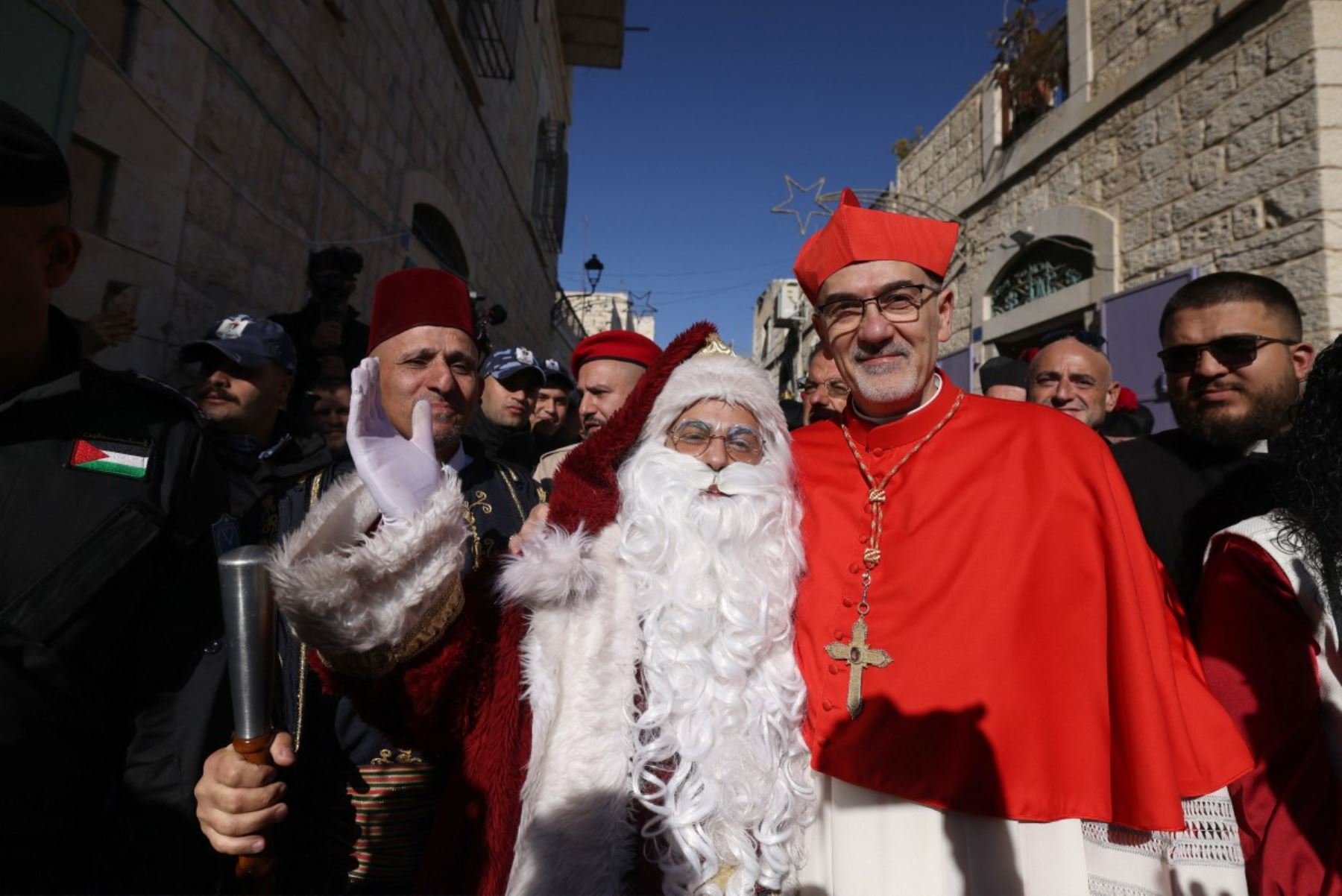 El patriarca latino de Jerusalén, el italiano Pierbattista Pizzaballa, posa para una fotografía con un hombre vestido de Papá Noel mientras es recibido por peregrinos, turistas y palestinos a su llegada para dirigir la misa de Navidad en la Iglesia de la Natividad en la ciudad de Belén, en Cisjordania ocupada por Israel, que se cree es el lugar de nacimiento de Jesucristo. AFP