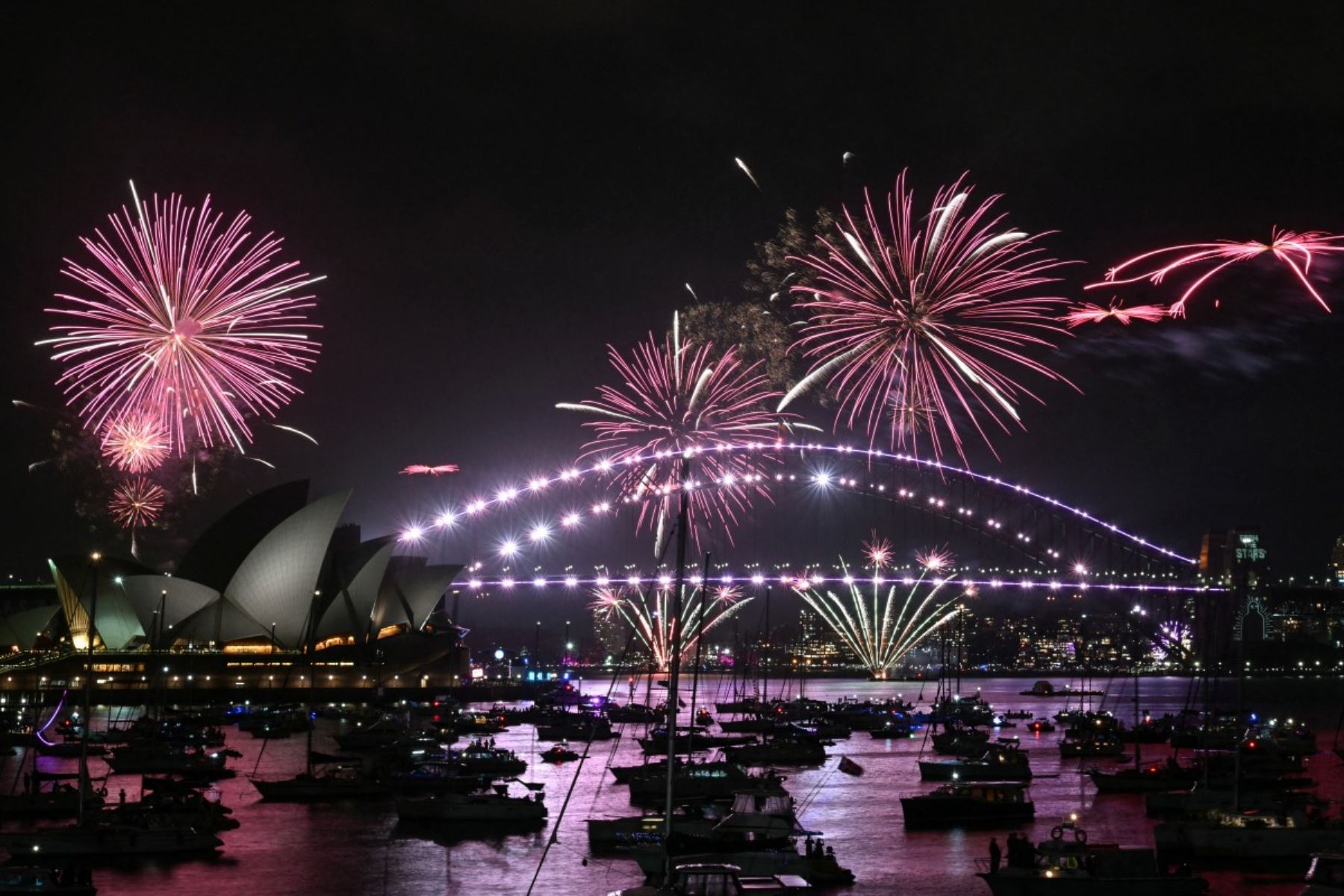 Los fuegos artificiales iluminan el cielo de medianoche sobre el Puente del Puerto de Sídney y la Ópera de Sídney durante las celebraciones del Día de Año Nuevo en Sídney. AFP
