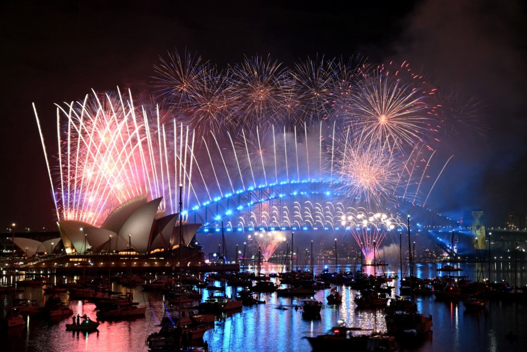 Los fuegos artificiales iluminan el cielo de medianoche sobre el Puente del Puerto de Sídney y la Ópera de Sídney durante las celebraciones del Día de Año Nuevo en Sídney. AFP
