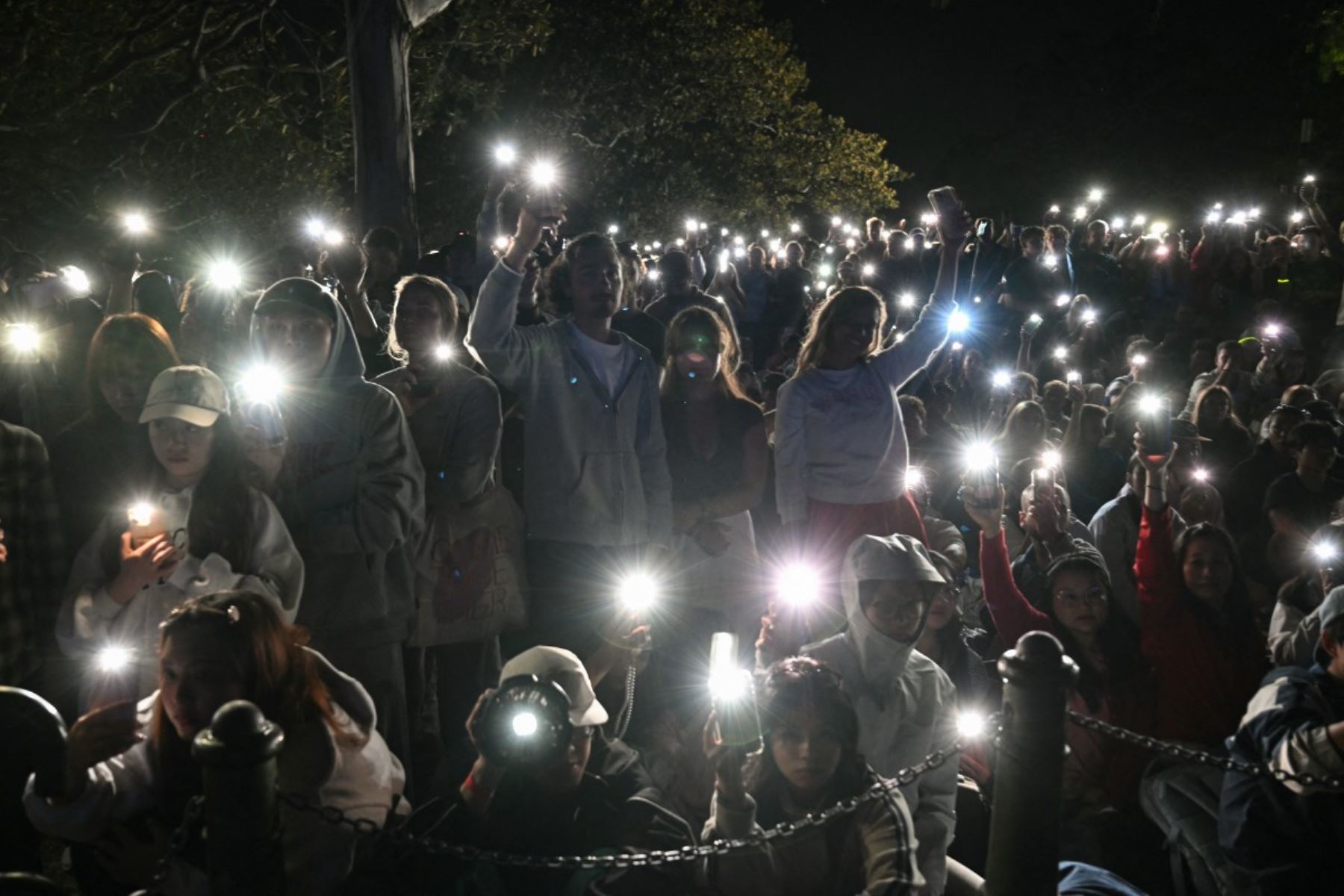 La gente enciende las linternas de sus teléfonos móviles mientras observa un minuto de silencio para reflexionar sobre el trágico ataque a tiros en Bondi Beach antes del espectáculo de fuegos artificiales de medianoche de Nochevieja en Sídney. AFP