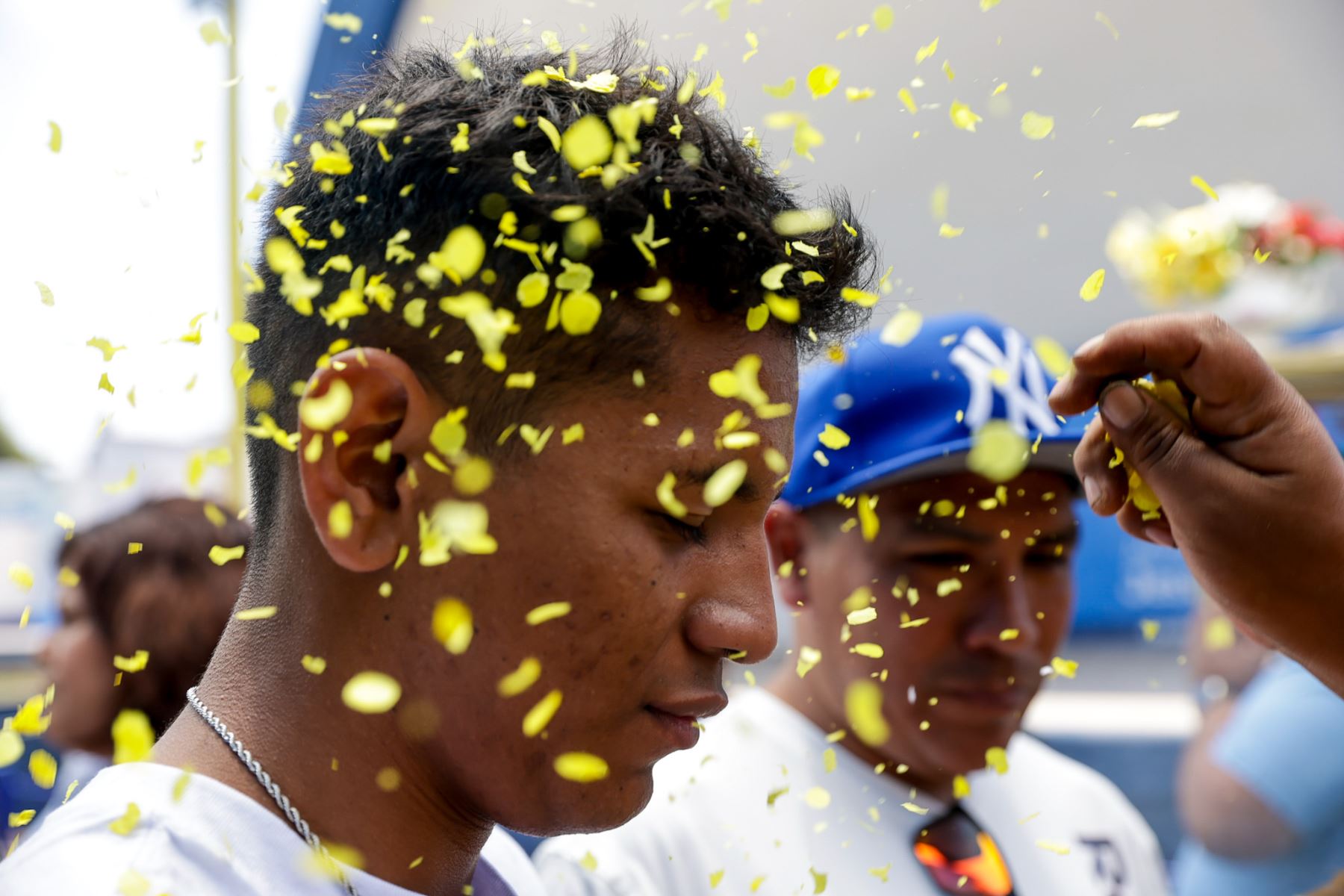 Pétalos de flores caen sobre un joven durante un baño de florecimiento, uno de los rituales más solicitados en la feria. El acto busca limpiar energías y atraer buenas oportunidades para el año siguiente, como parte de prácticas ancestrales que combinan símbolos naturales, fe y tradición andina. Foto: ANDINA/Luis Iparraguirre