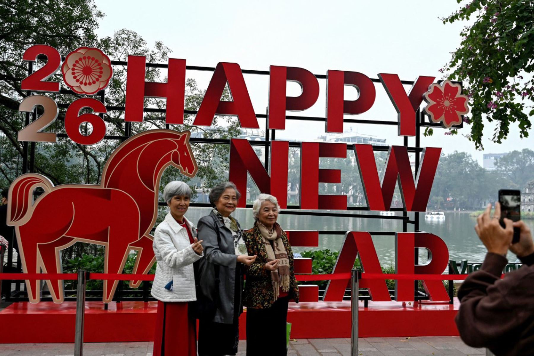 Mujeres posan para fotos junto al lago Hoan Kiem, junto a una instalación de Año Nuevo en Hanoi, el 31 de diciembre de 2025. 
Foto: AFP