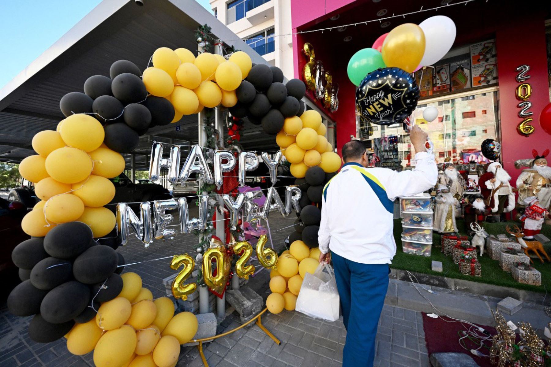 Un hombre entra en una tienda decorada con globos que dicen "2026" antes del Año Nuevo en la ciudad de Kuwait el 31 de diciembre de 2025. 
Foto: AFP