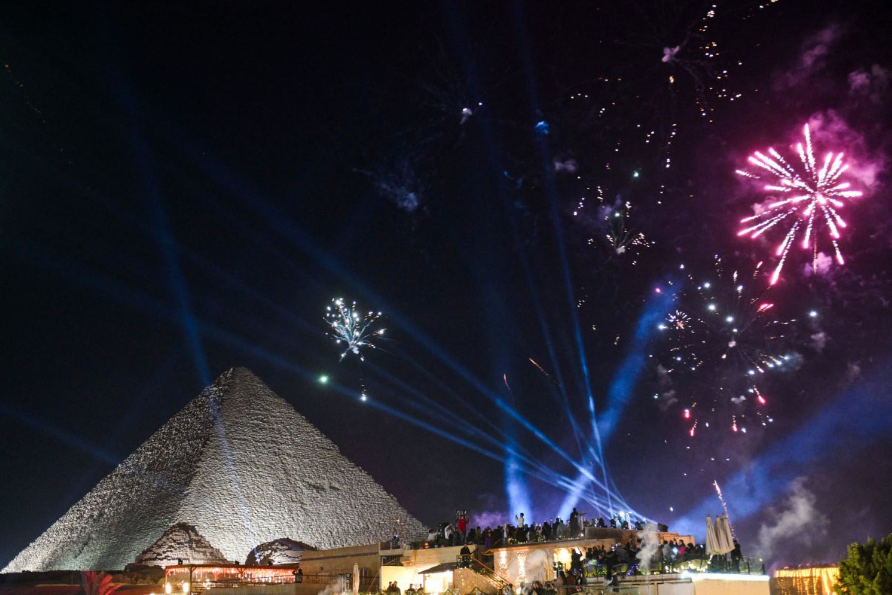 La gente observa los fuegos artificiales que iluminan el cielo sobre las Grandes Pirámides de Giza, en las afueras de El Cairo, durante las celebraciones de Año Nuevo, a primera hora del 1 de enero de 2026. 
Foto: AFP