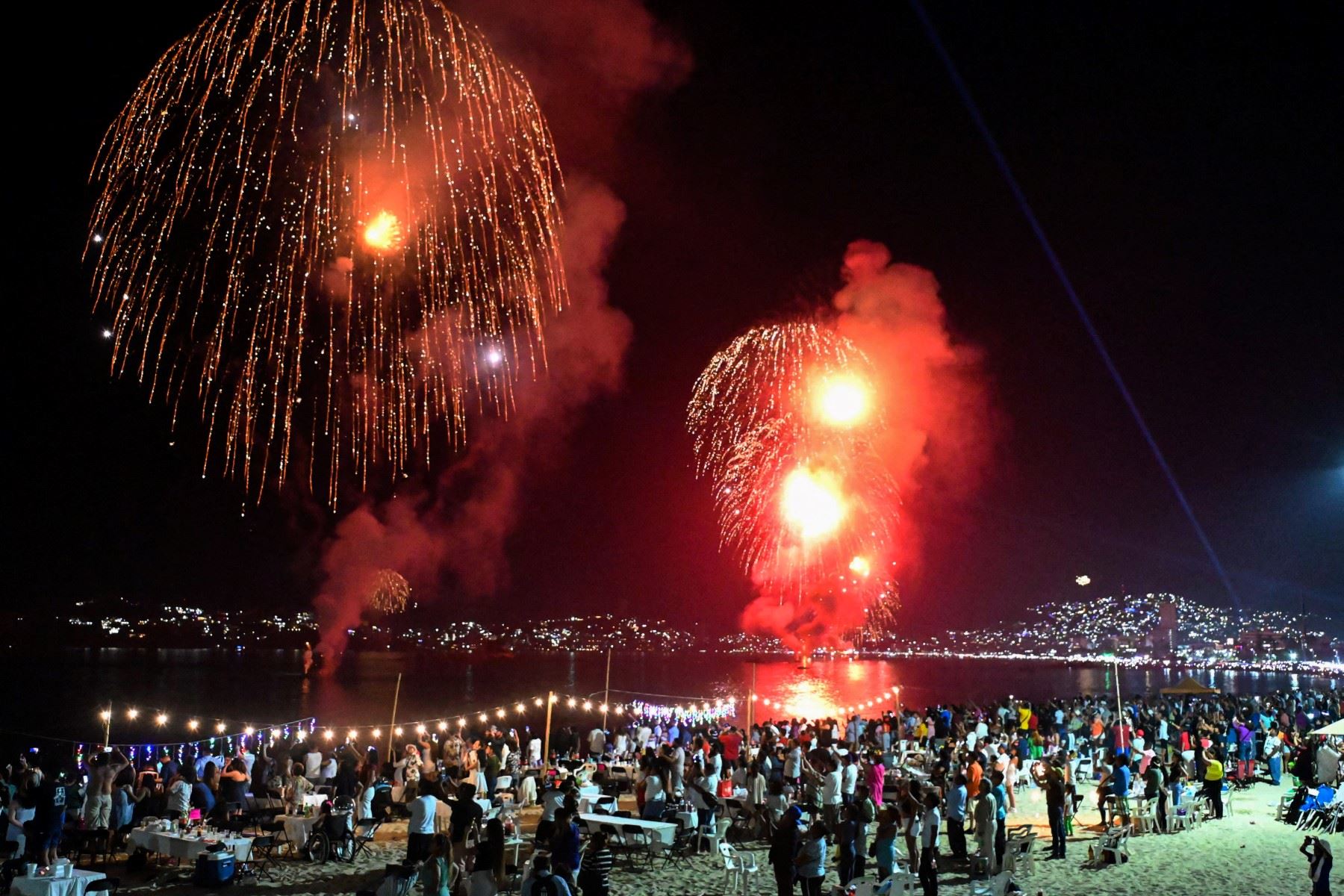 La gente ve los fuegos artificiales mientras se disparan en la Bahía de Acapulco durante las celebraciones de Nochevieja en Acapulco, Estado de Guerrero, el 1 de enero de 2024. (Foto de FRANCISCO ROBLES / AFP)
