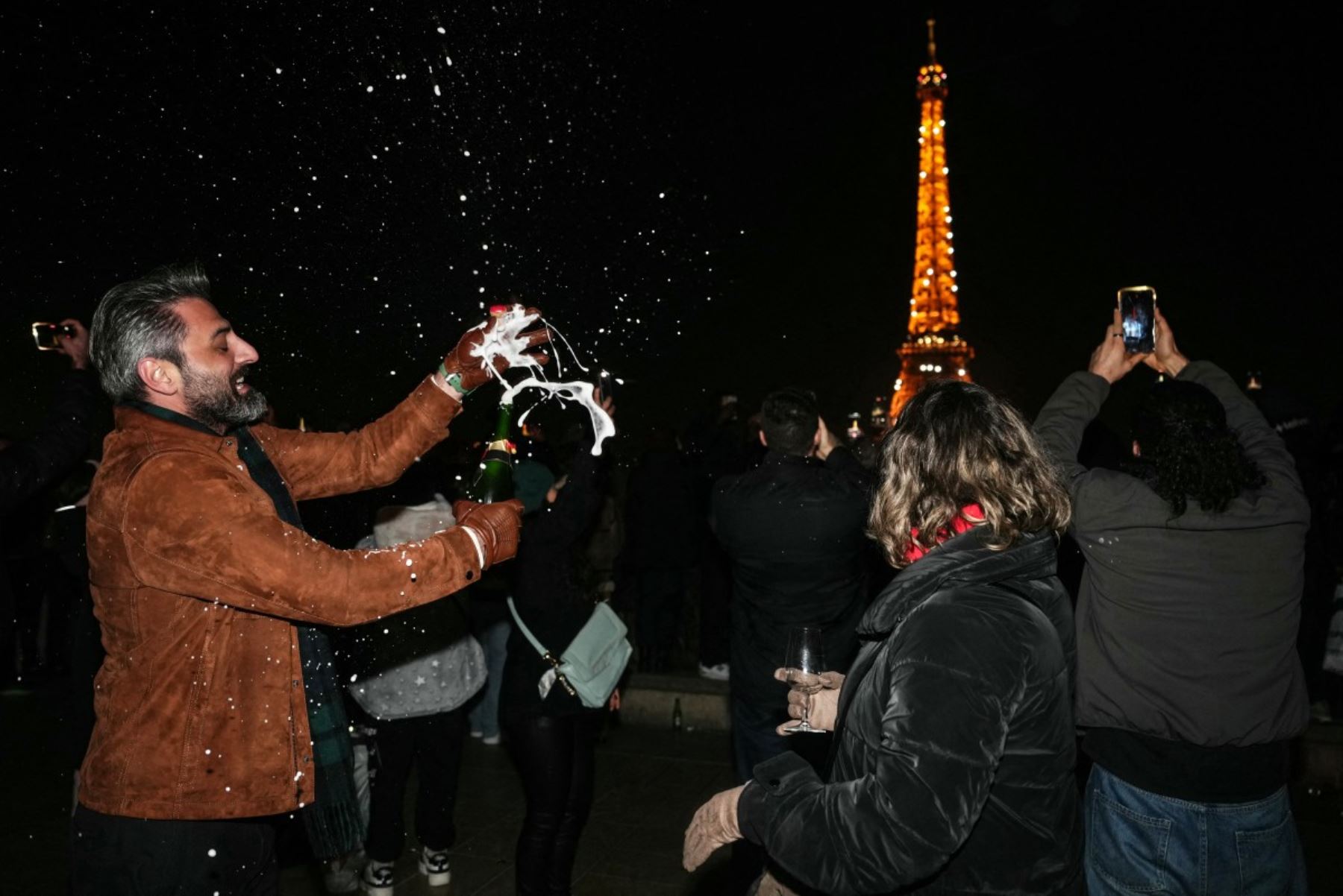 Un ciudadano abre una botella de champán cerca de la Torre Eiffel para dar la bienvenida al Año Nuevo, en el centro de París, el 31 de diciembre de 2025. (Foto de Dimitar DILKOFF / AFP)