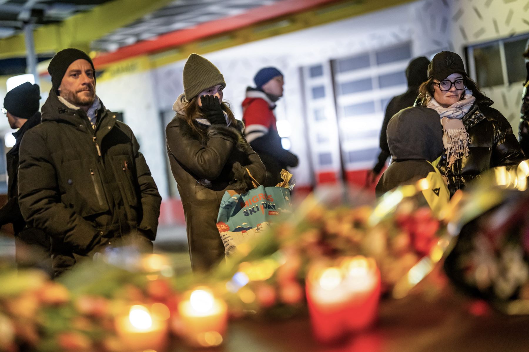 Los dolientes se reúnen frente a flores y velas colocadas cerca del lugar donde un incendio arrasó un bar abarrotado durante las celebraciones de Nochevieja en la estación de esquí alpina de Crans-Montana. Foto: AFP