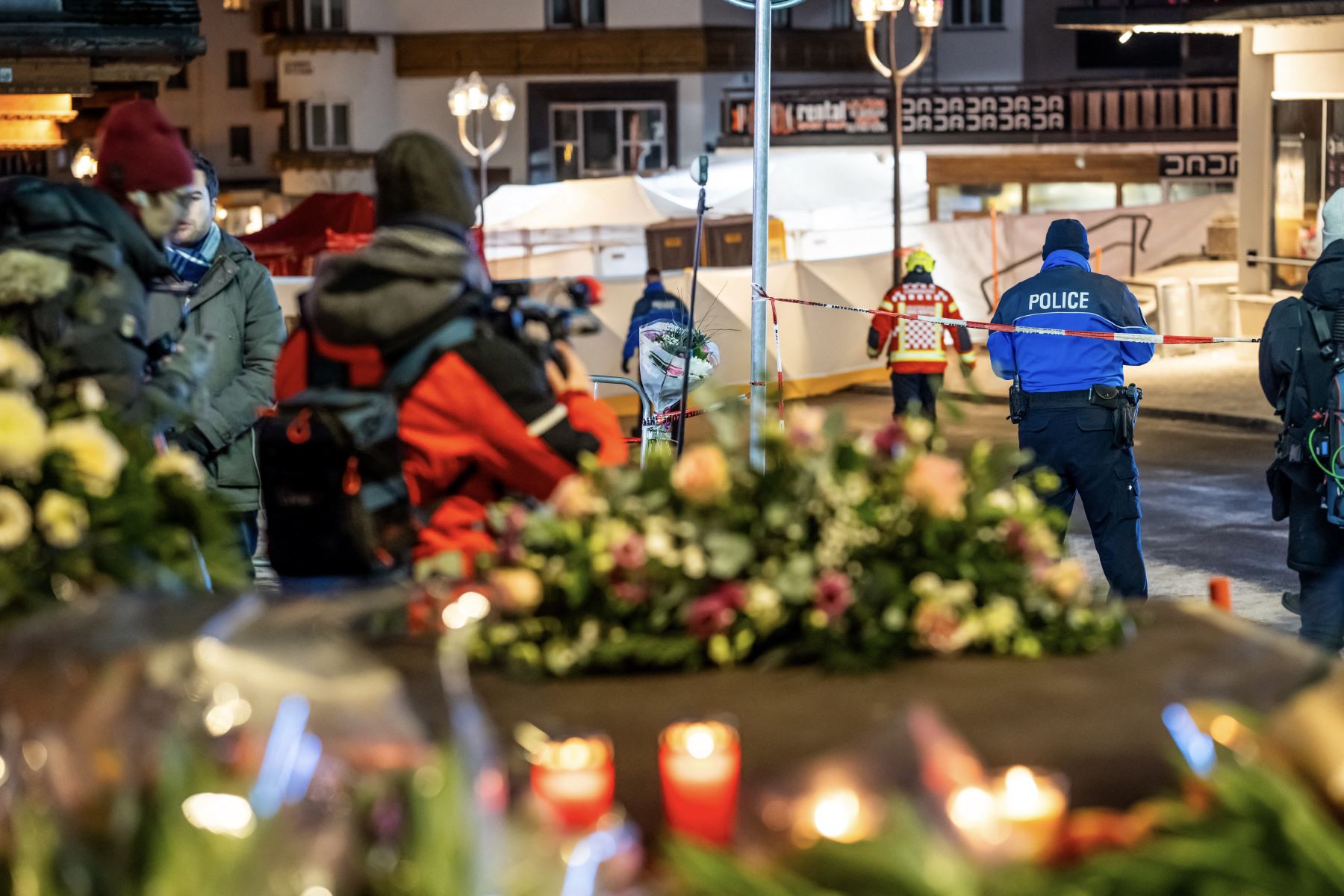 Los dolientes se reúnen frente a flores y velas colocadas cerca del lugar donde un incendio arrasó un bar abarrotado durante las celebraciones de Nochevieja en la estación de esquí alpina de Crans-Montana. Foto: AFP